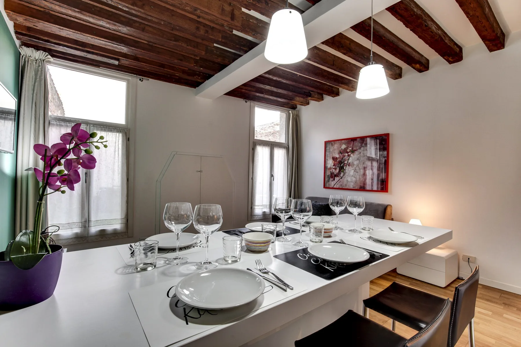 A dining area with a long table set with dishes and glassware.