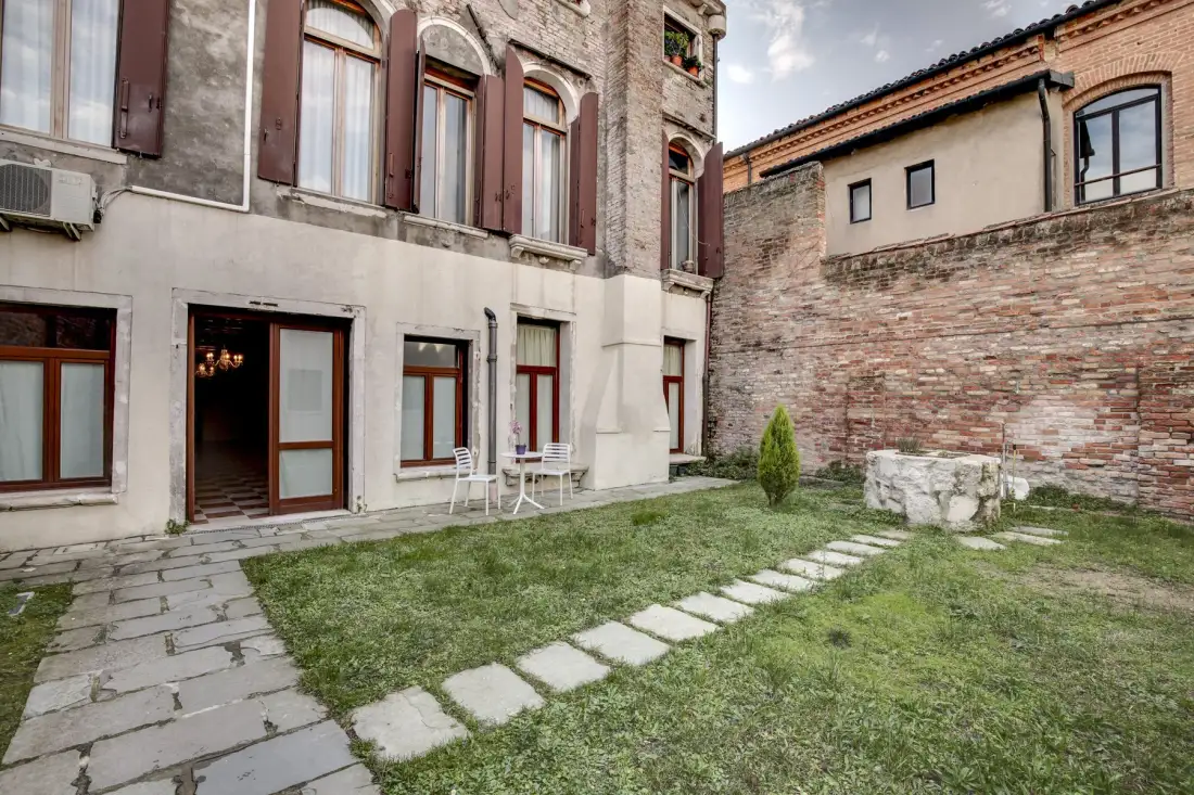 A stone courtyard beside a building, with a paved path and outdoor seating.