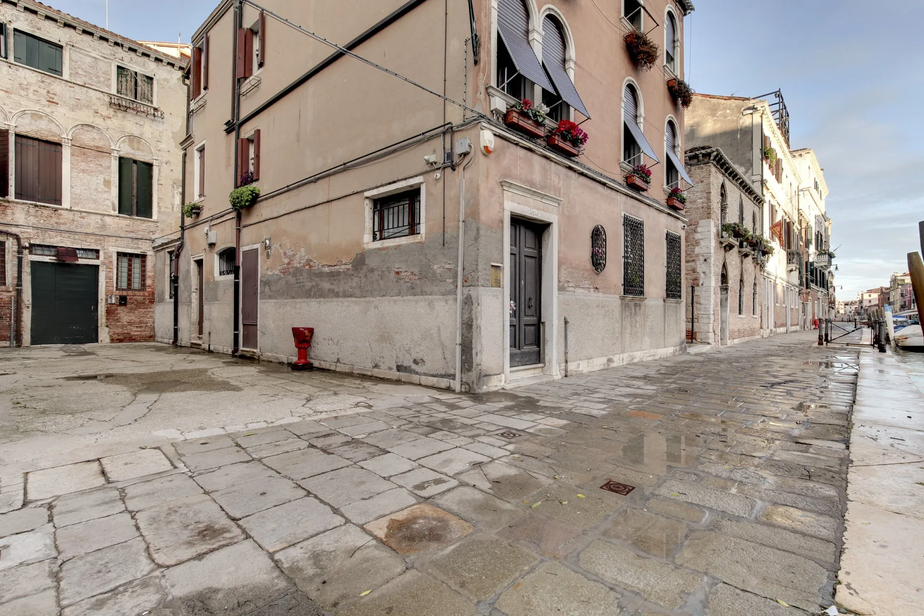 A narrow paved street runs past closely spaced residential buildings.