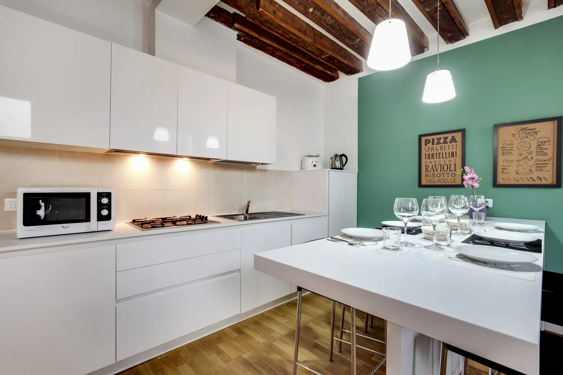 A modern kitchen with a dining table set with plates and glassware.