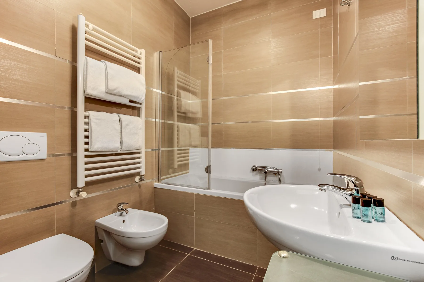 A tiled bathroom with a bathtub, sink, and towel warmer.