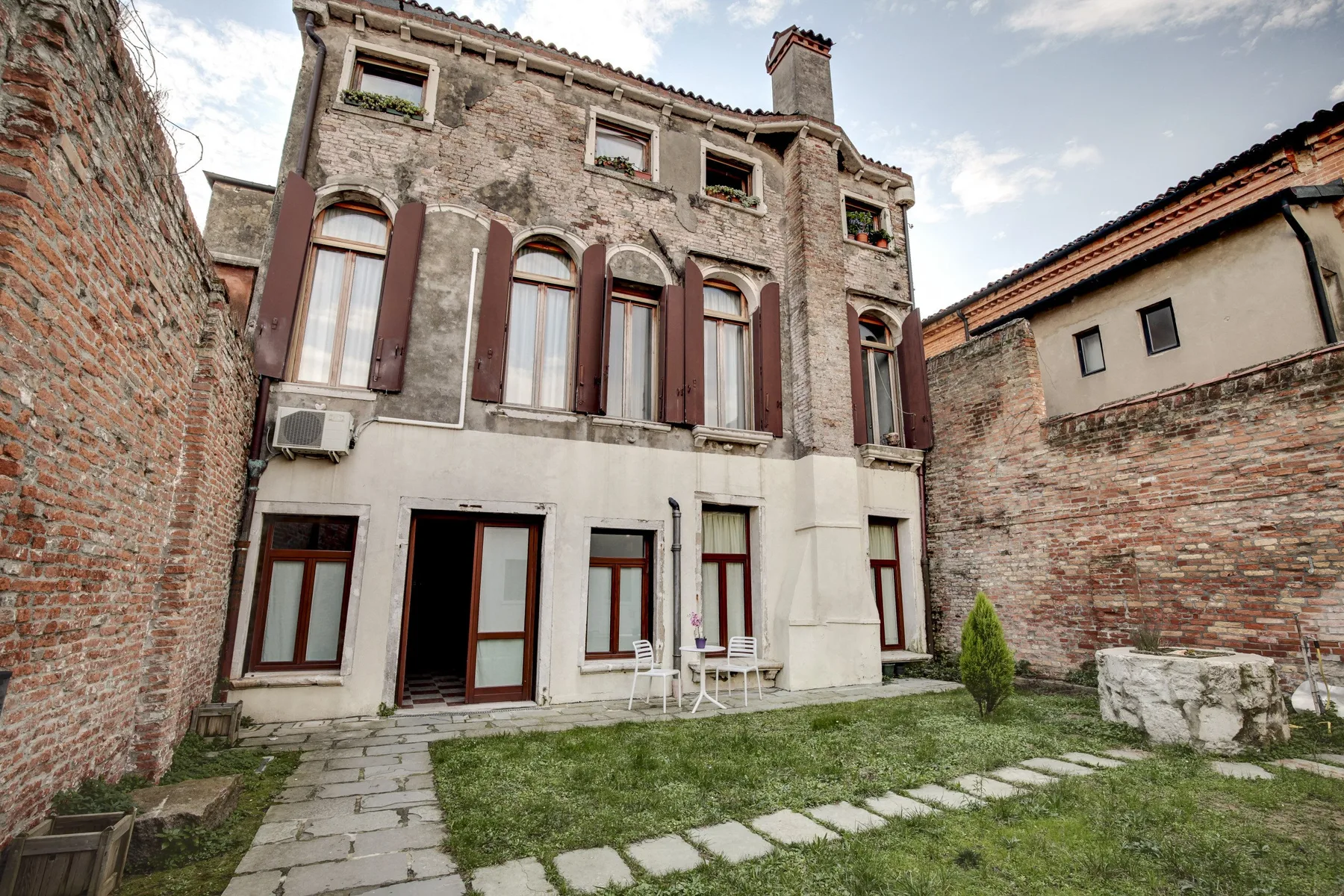 An old stone building faces a small courtyard with a grassy lawn.
