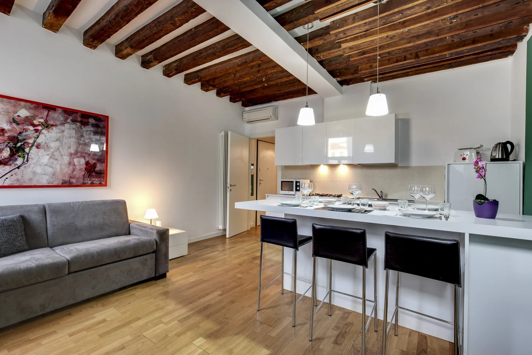 An open-plan living and kitchen area with a sofa and a counter with seating.