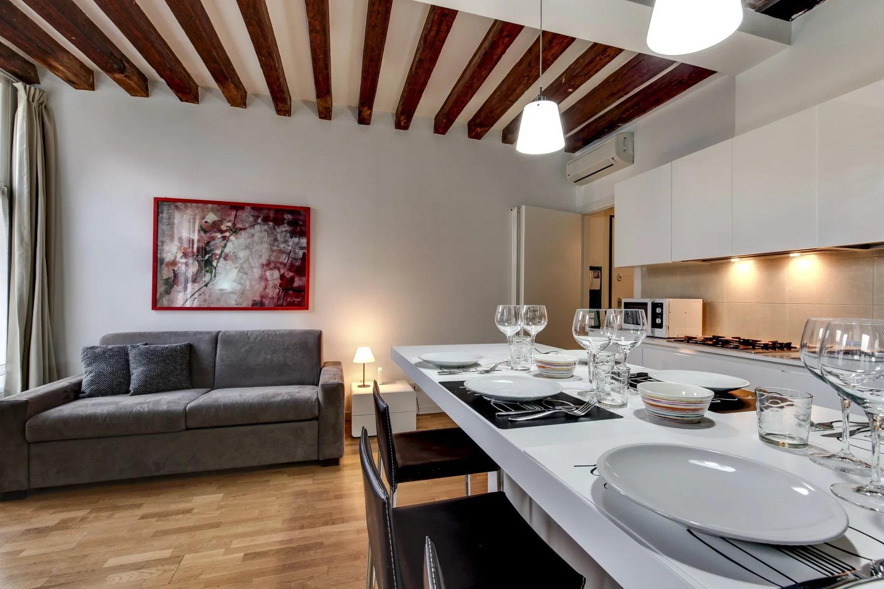 A dining area with a set table and a sofa beside it.