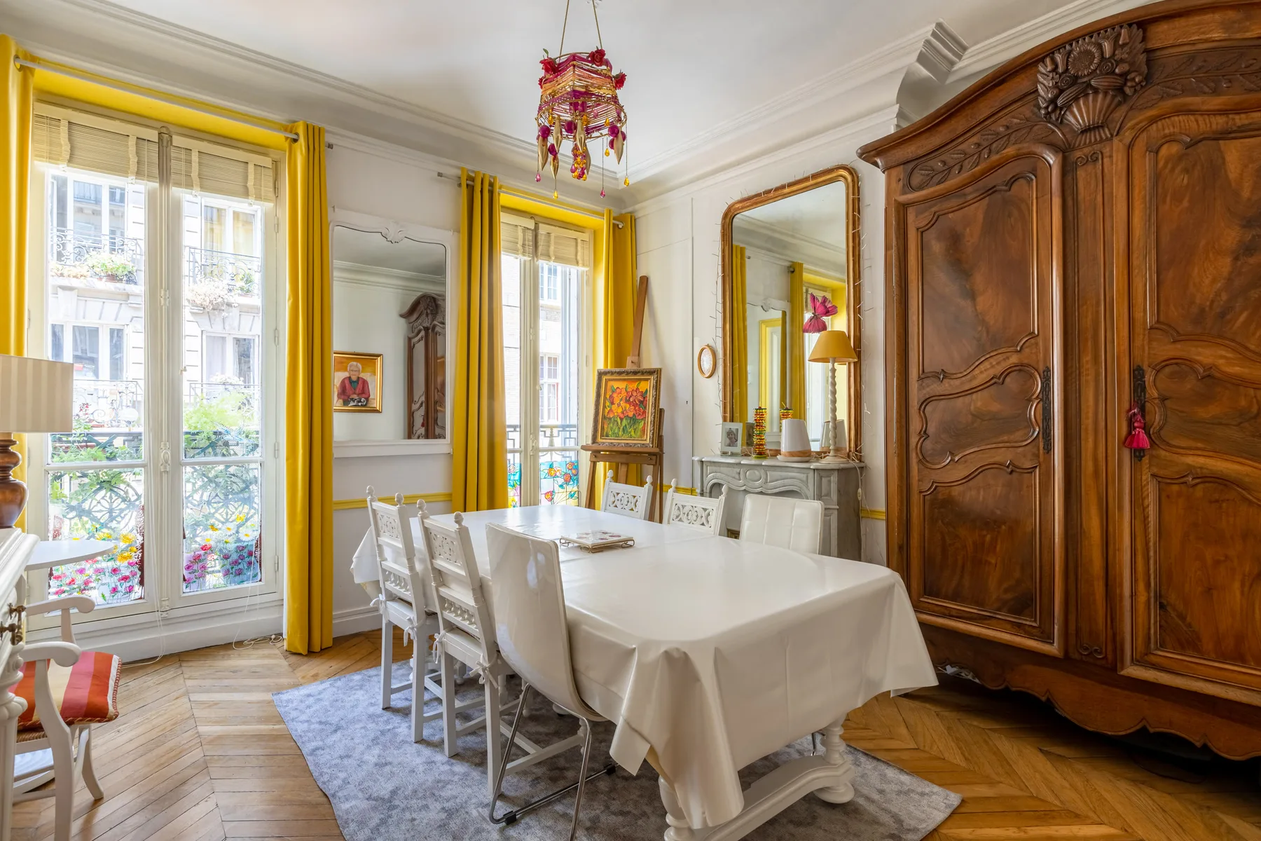 Un comedor con una mesa larga bajo una lámpara colgante de colores.