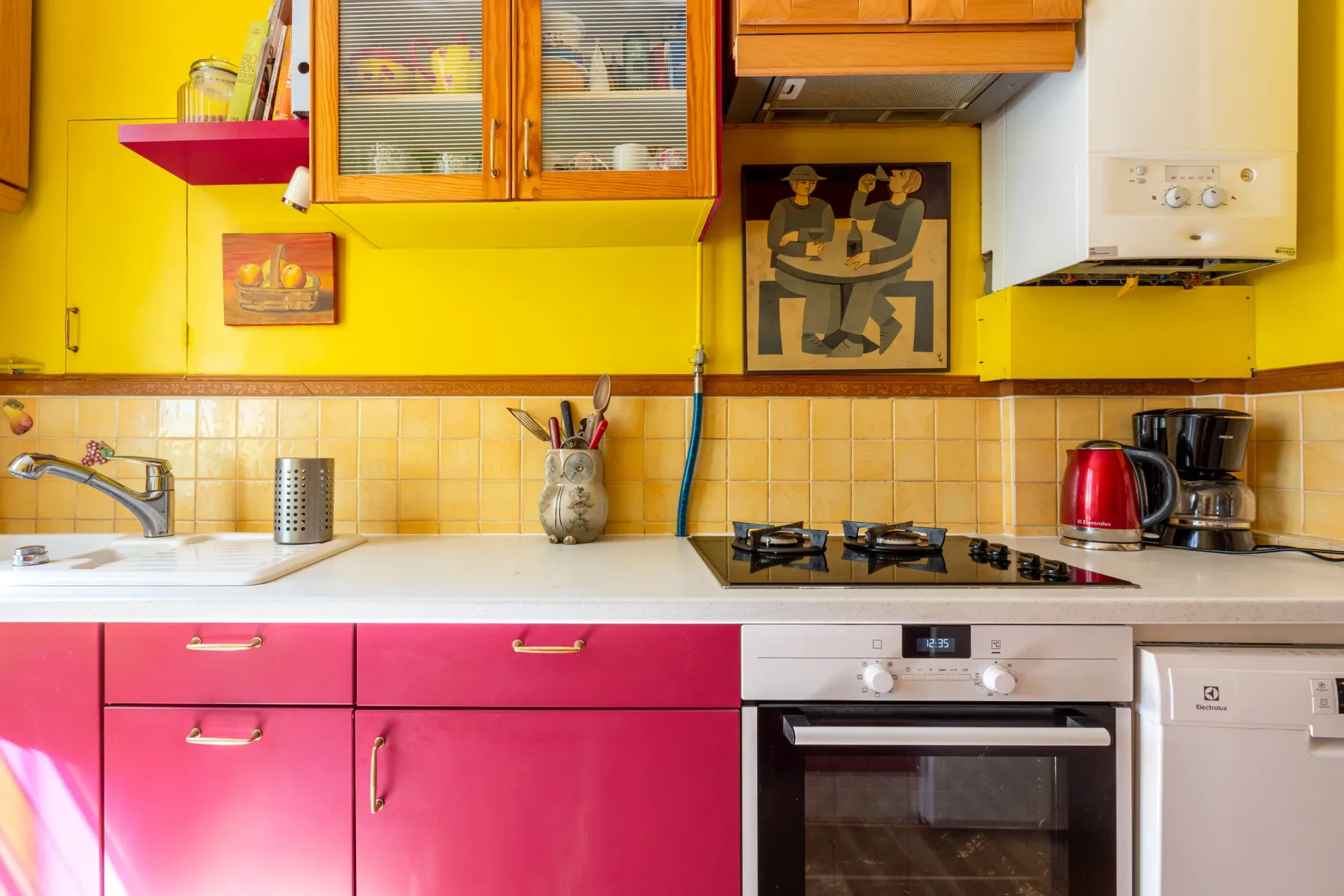 Una cocina colorida con gabinetes rosas, una encimera y una estufa.