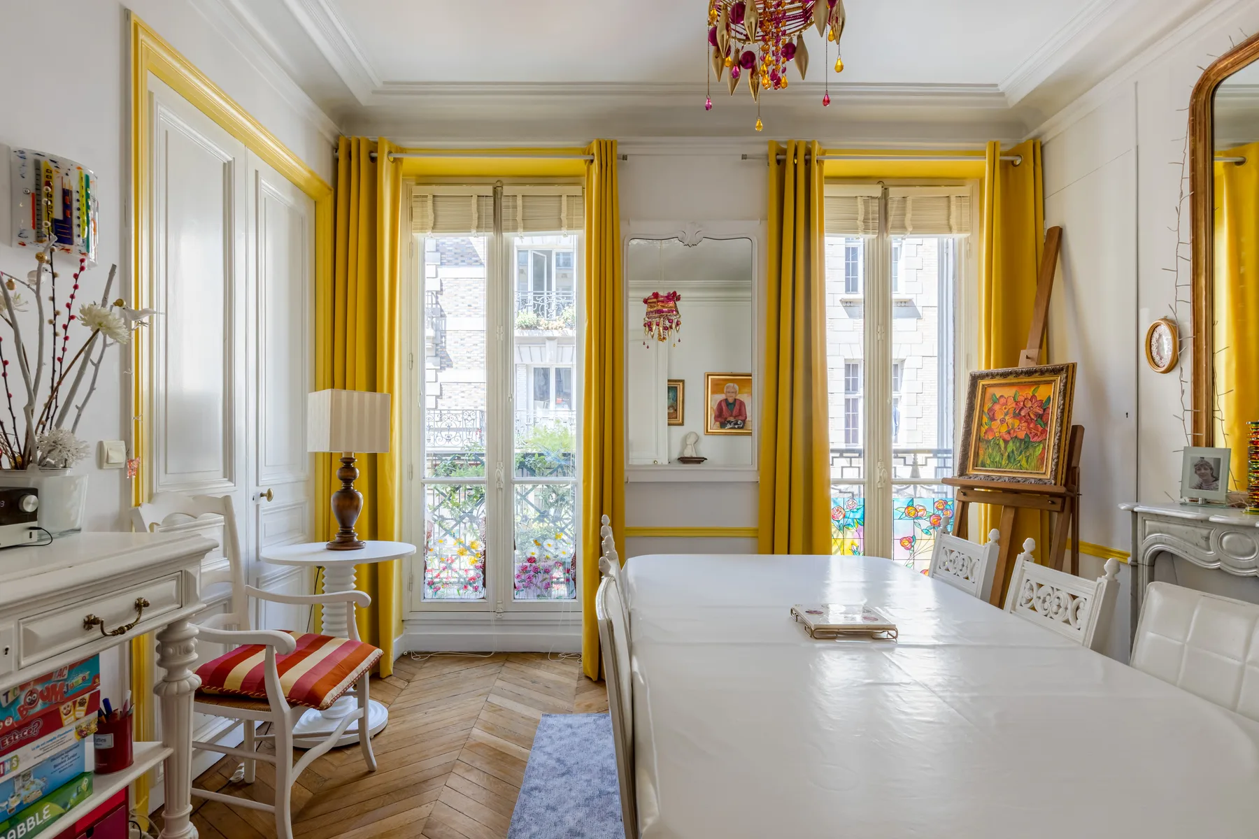 Un comedor luminoso con una mesa larga, ventanas altas y cortinas amarillas.