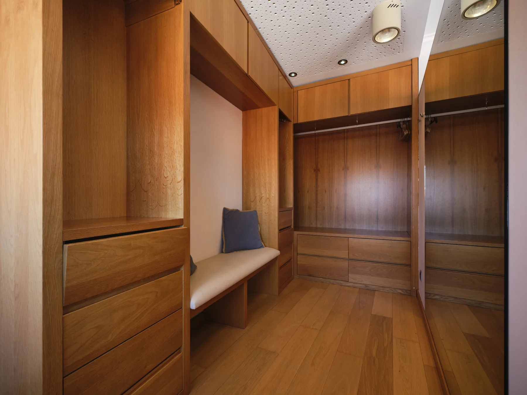 A wood-paneled dressing room with built-in storage and a cushioned bench.