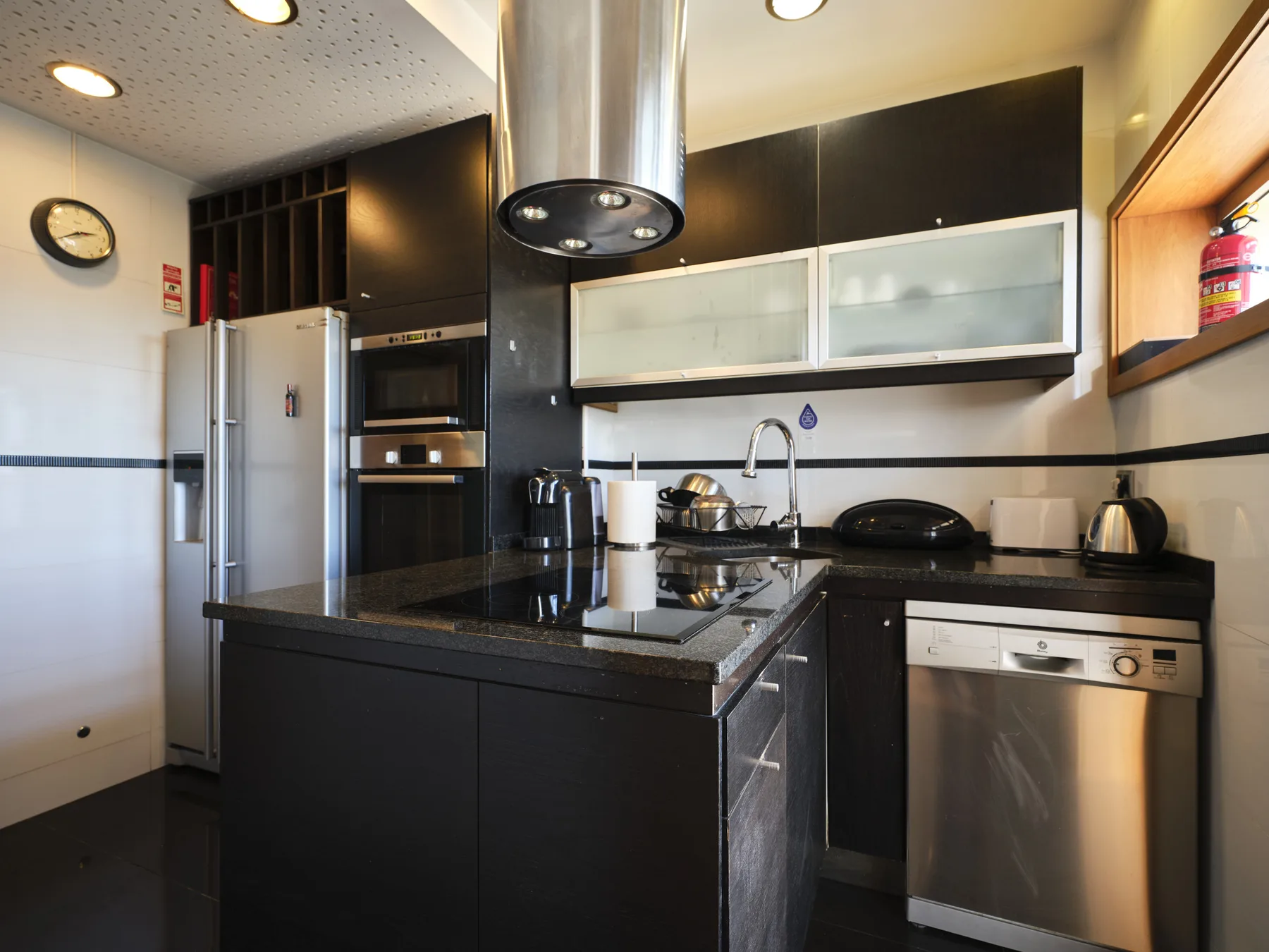 A modern kitchen with dark cabinets, a central island, and stainless steel appliances.