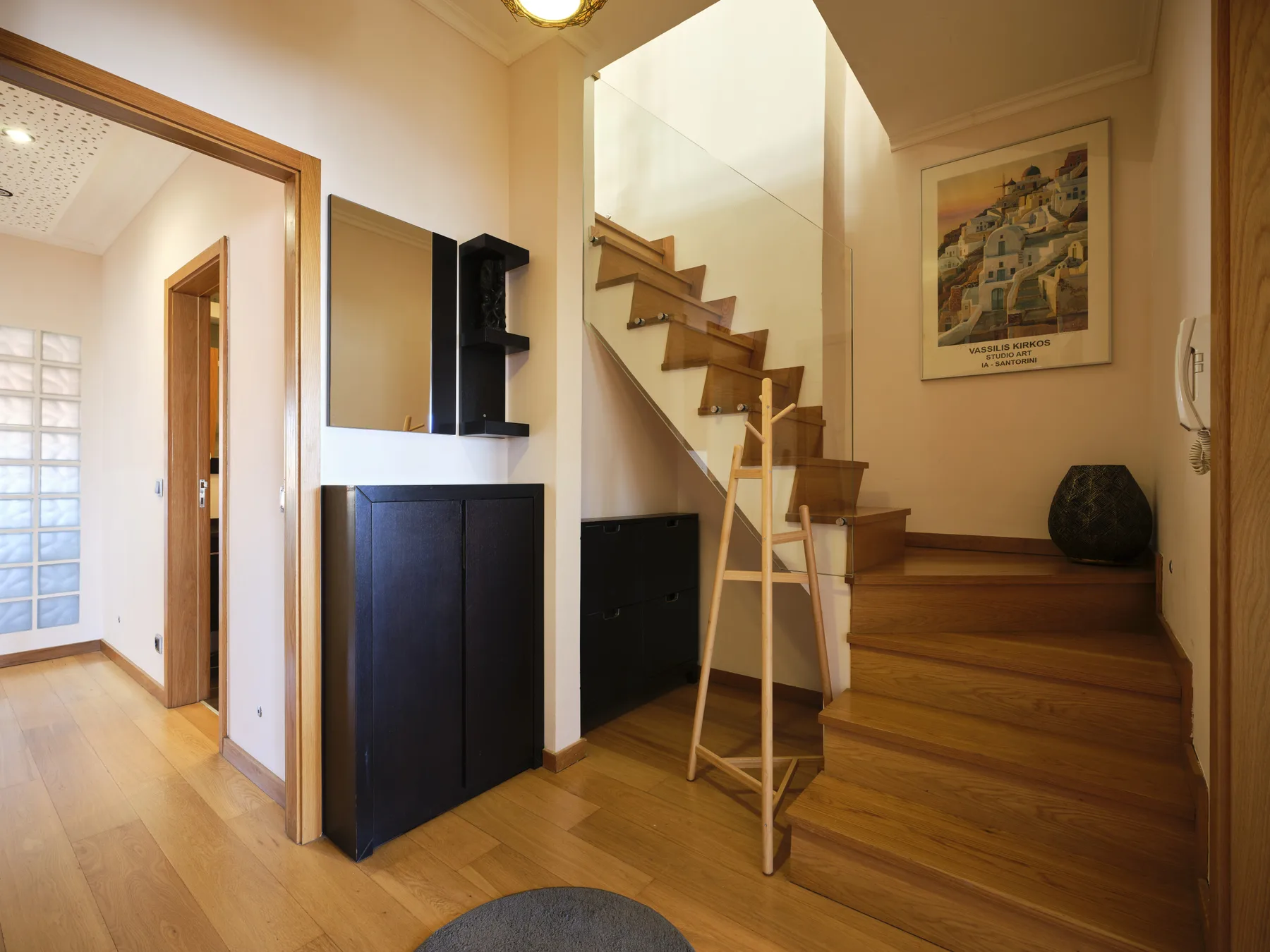 A wooden staircase rises beside a small landing in a warm-toned interior.