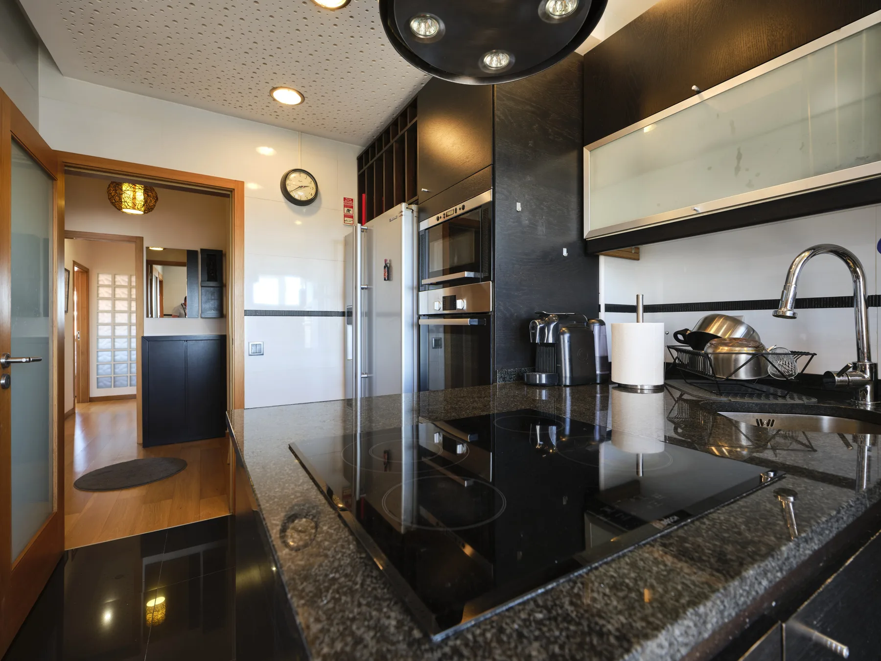 A modern kitchen with a black countertop, cooktop, and sink.