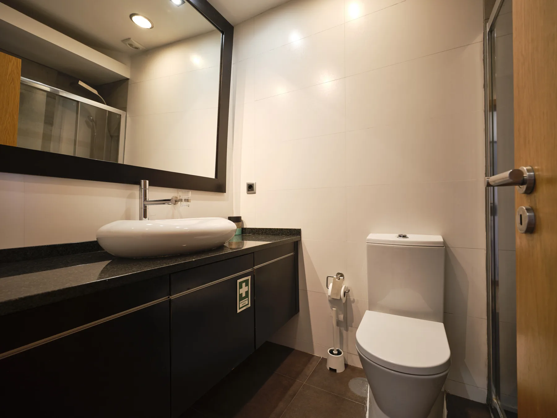 A bathroom with a vessel sink, dark vanity, and toilet.