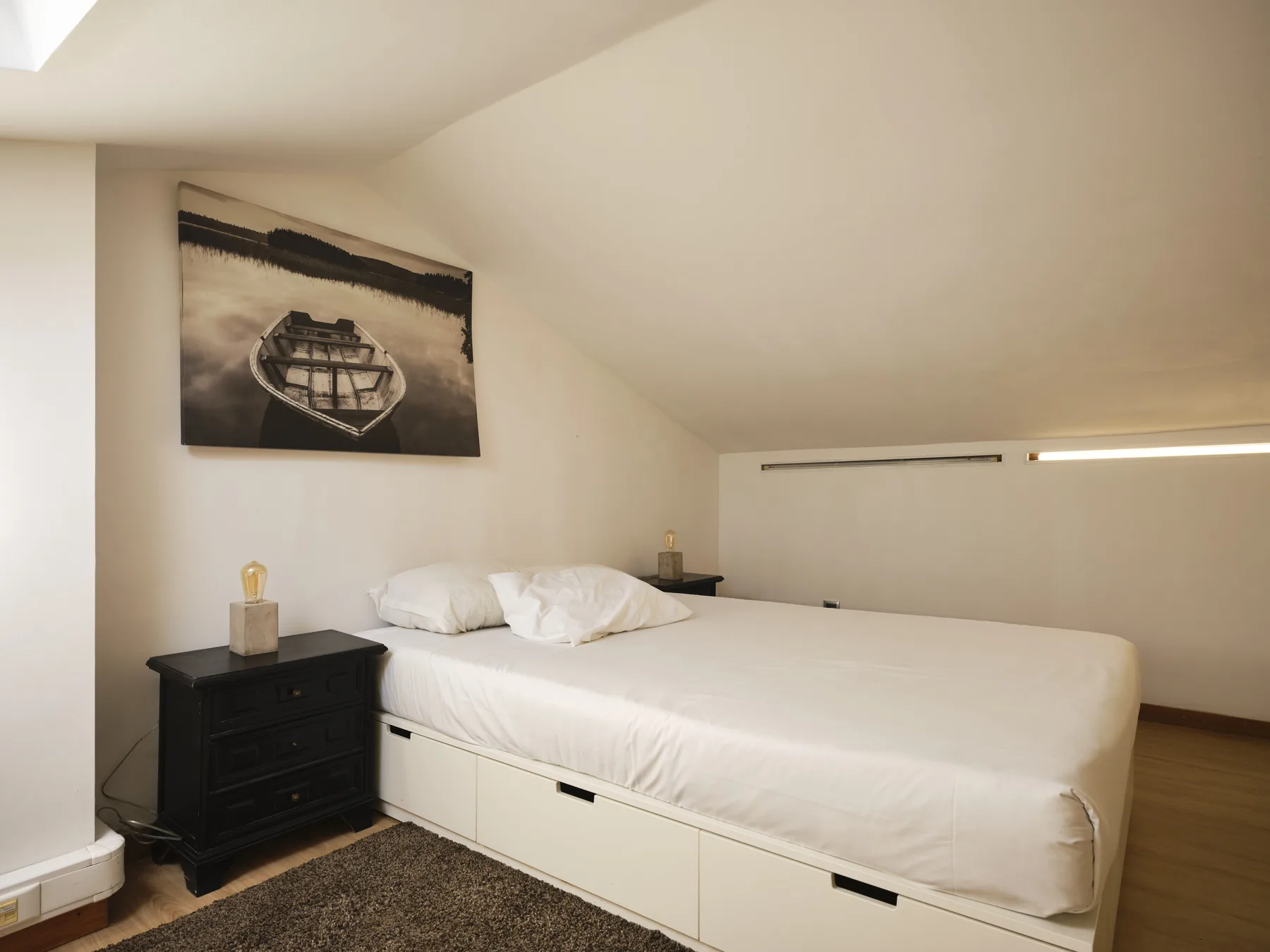 A bedroom with a low bed beneath a sloped ceiling.