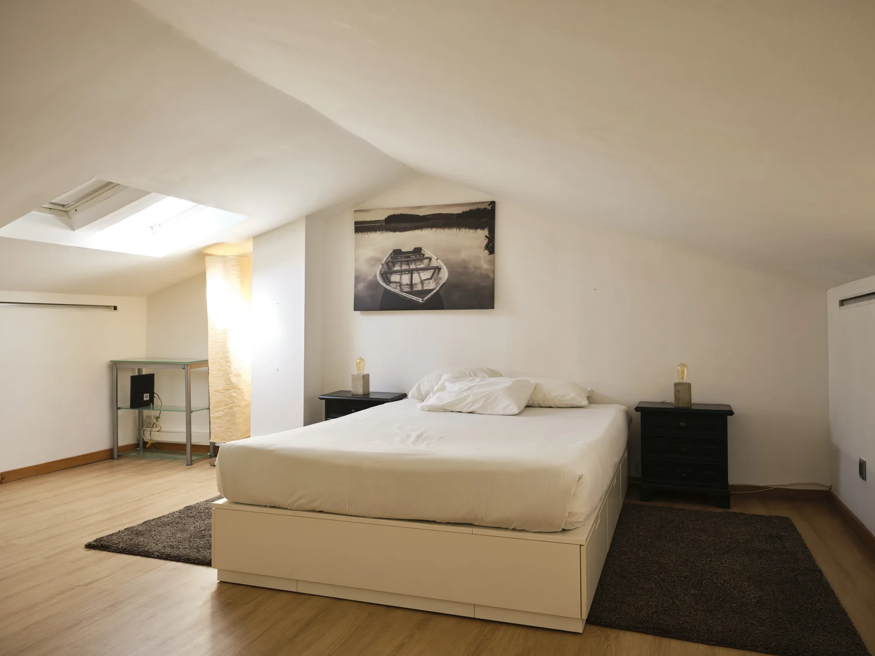 A bedroom with a bed, bedside tables, and a framed picture on the wall.