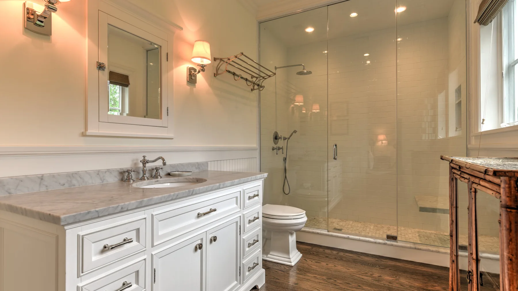 Un baño luminoso con lavabo doble, inodoro y ducha de vidrio.