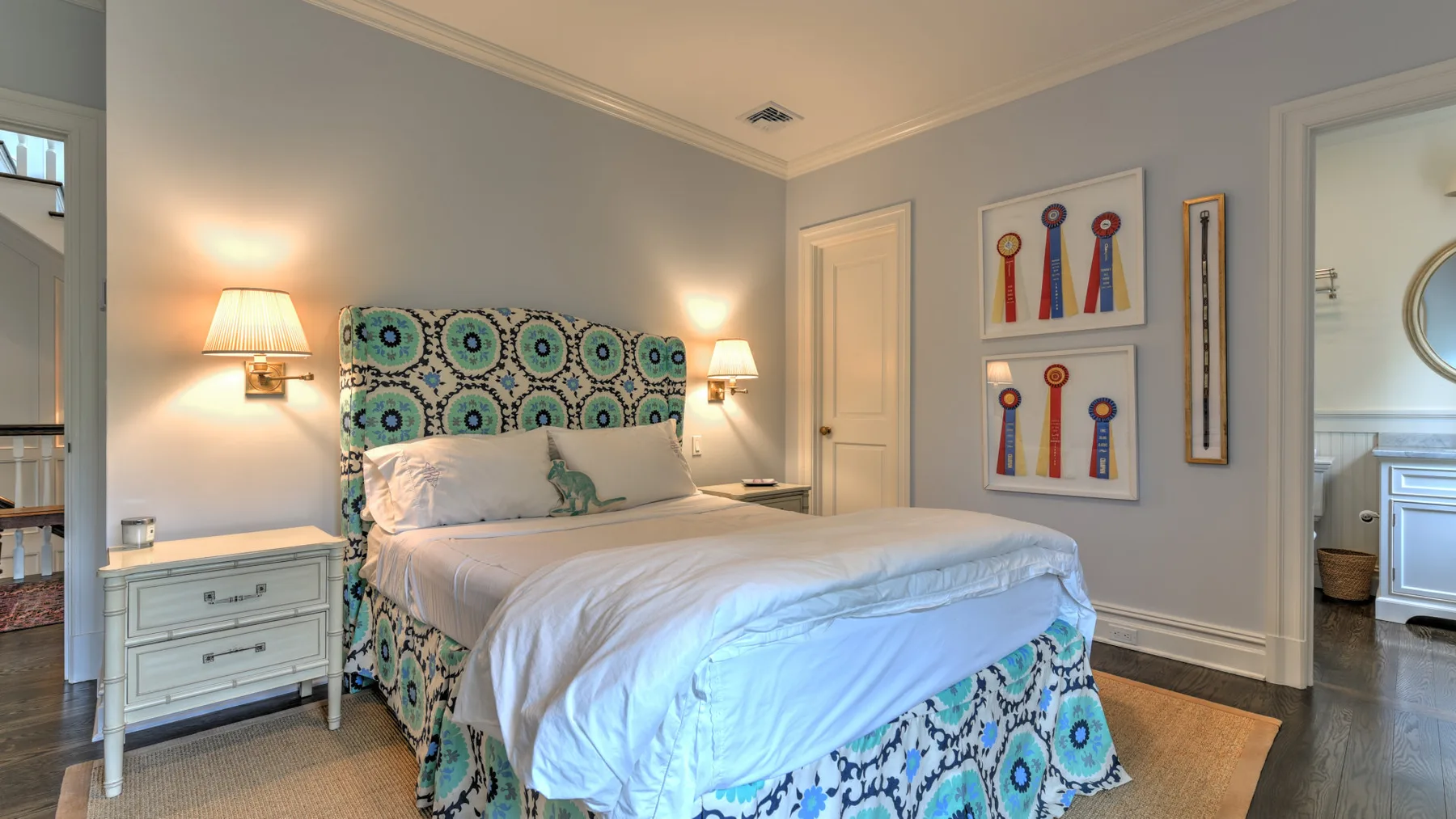 Un dormitorio con una cama estampada, mesitas de noche y cuadros enmarcados.