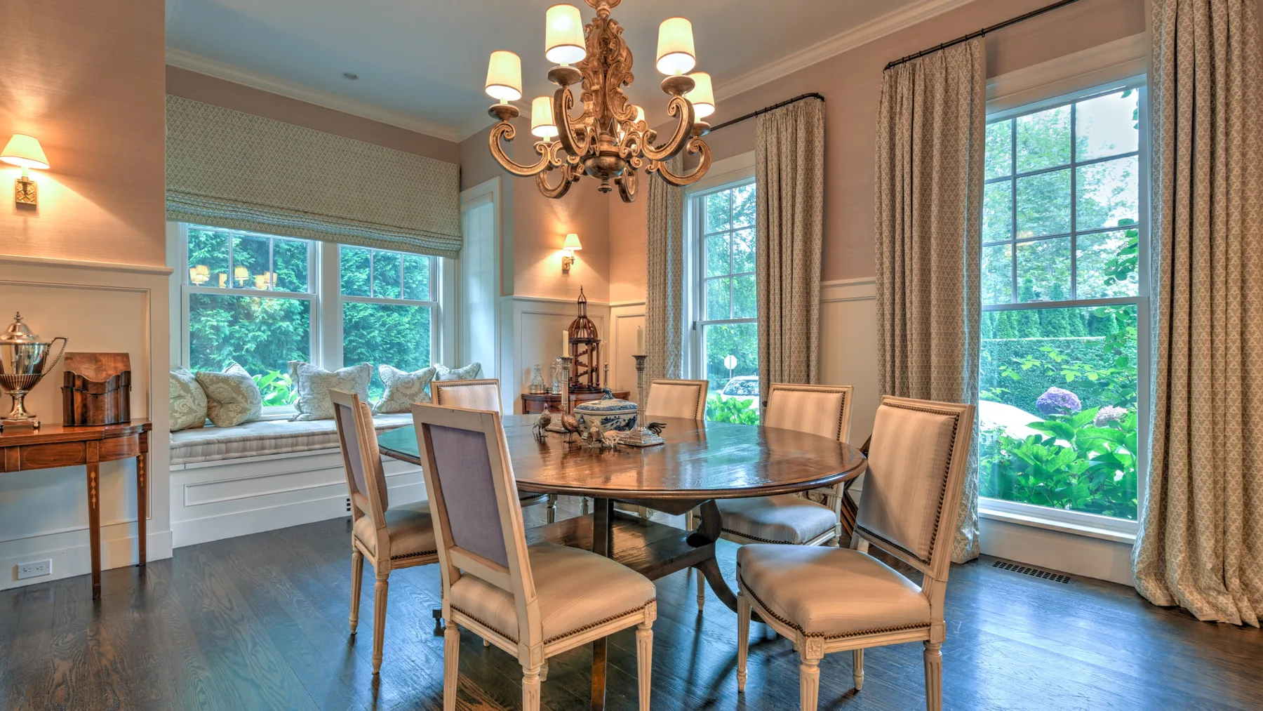 Un comedor con una mesa y sillas junto a grandes ventanas.