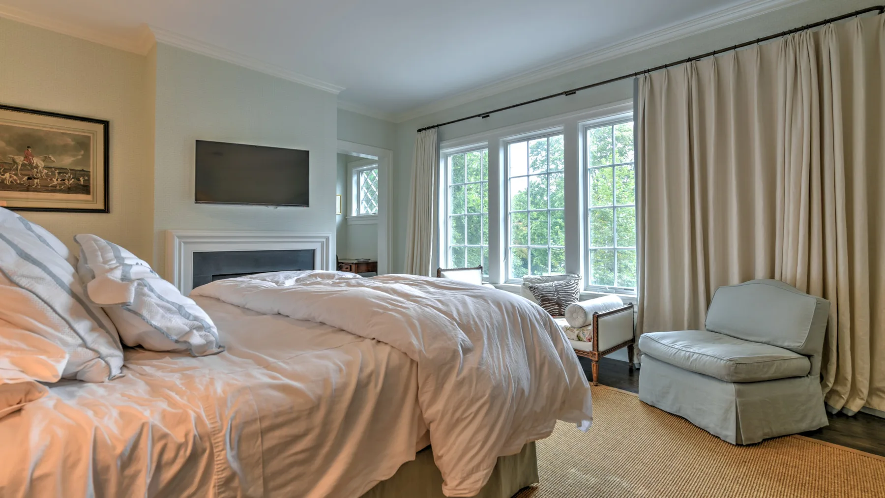 Dormitorio con camas junto a grandes ventanas y una zona de estar con cortinas.