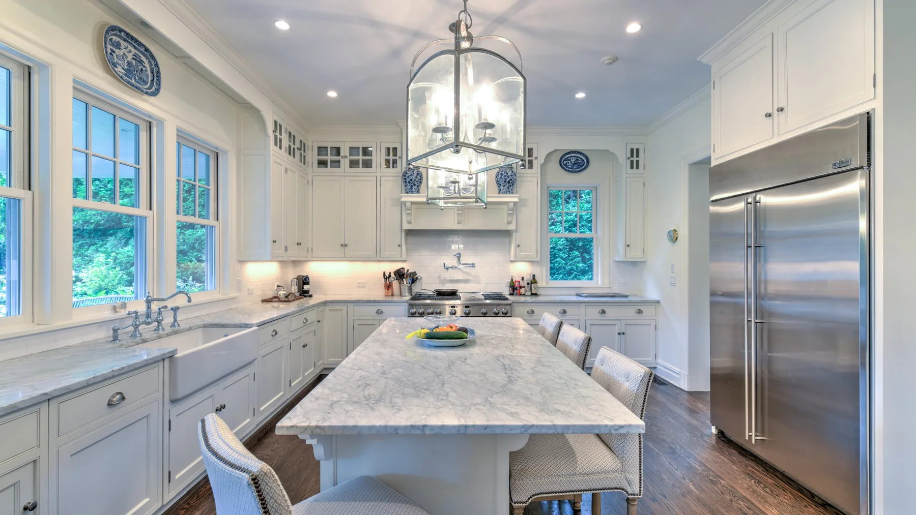 Una cocina luminosa con gabinetes blancos, una isla central y electrodomésticos de acero inoxidable.