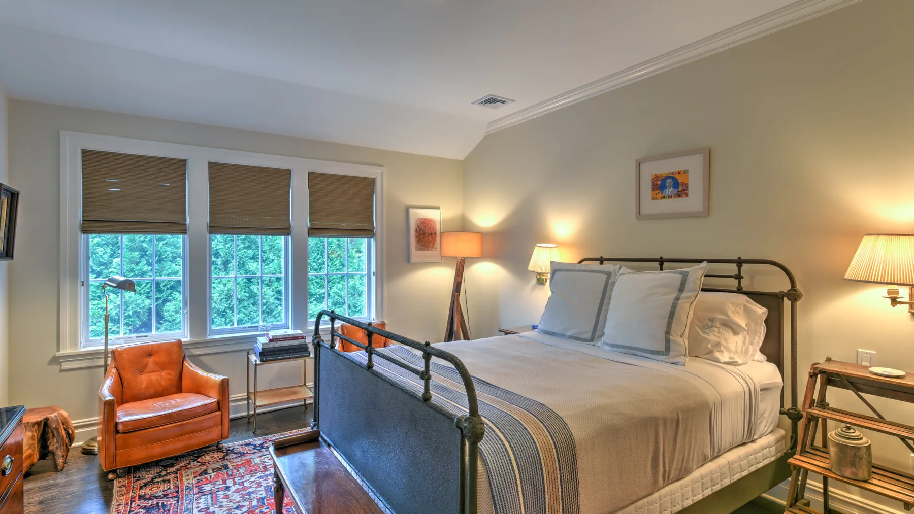 Un dormitorio con una cama grande, un sillón y ventanas con persianas.