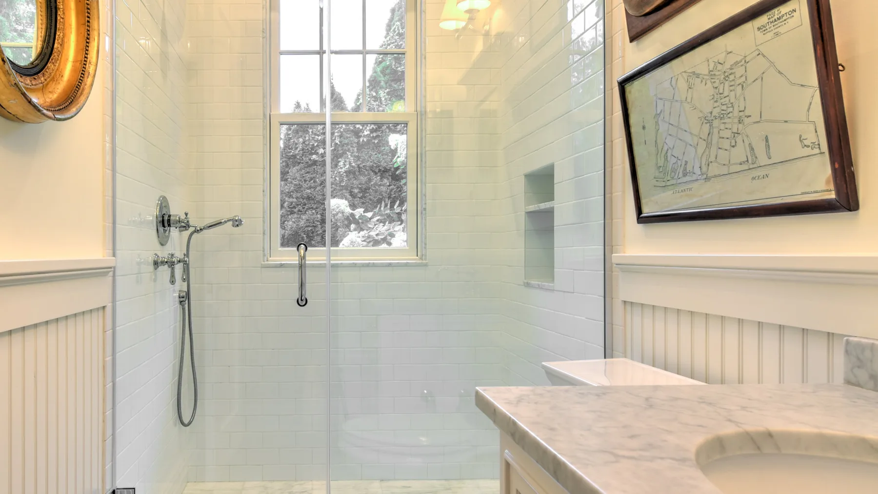 Un baño luminoso con azulejos, ventana, ducha y tocador de piedra.