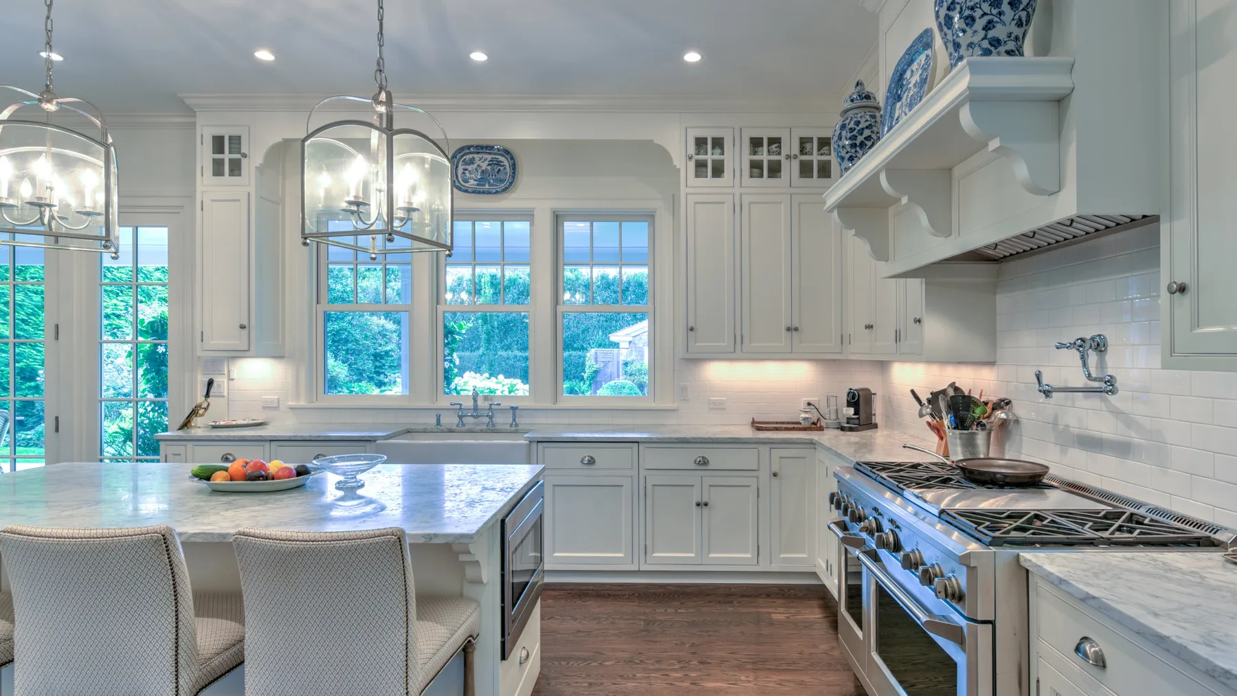 Una cocina luminosa con una isla central, armarios blancos y ventanas grandes.