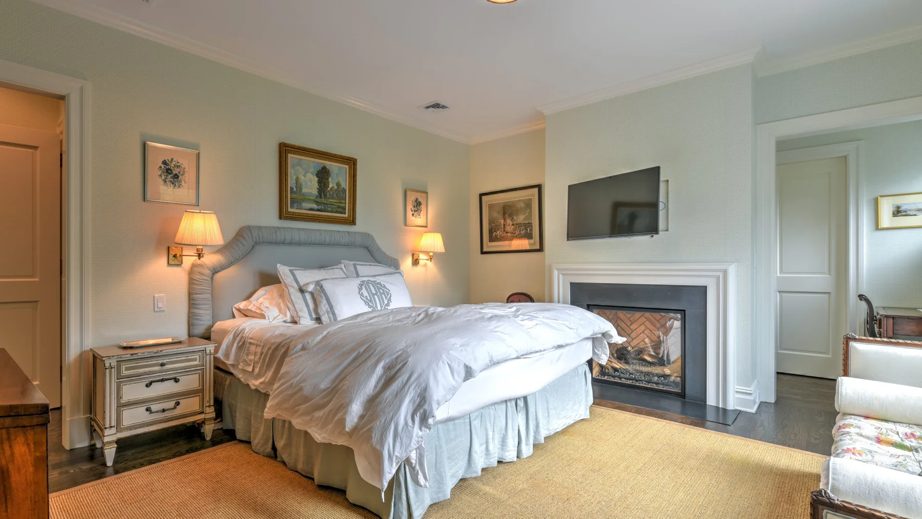 Un dormitorio con una cama tendida y una chimenea junto a la pared.