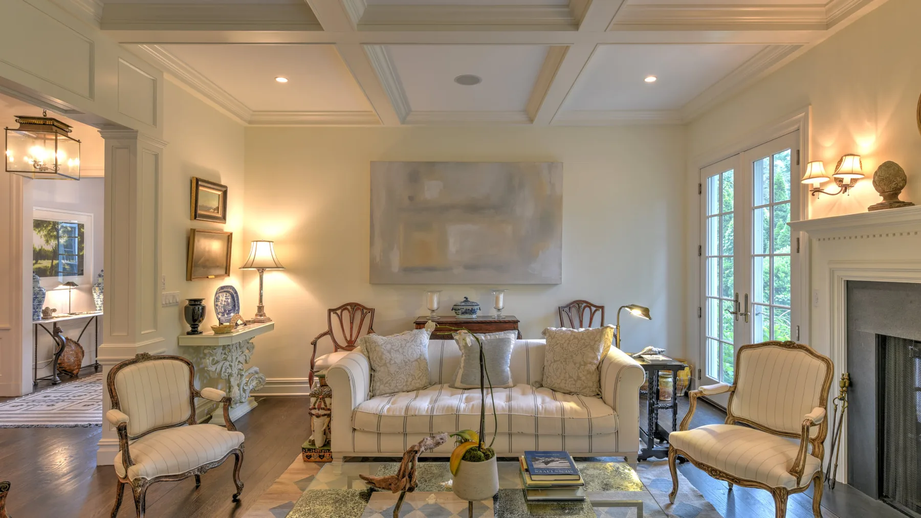Una sala luminosa con sofá, sillones y ventanas altas.