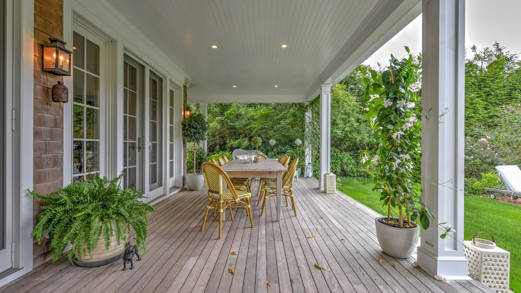 Comedor exterior cubierto con una mesa y sillas sobre una terraza de madera.