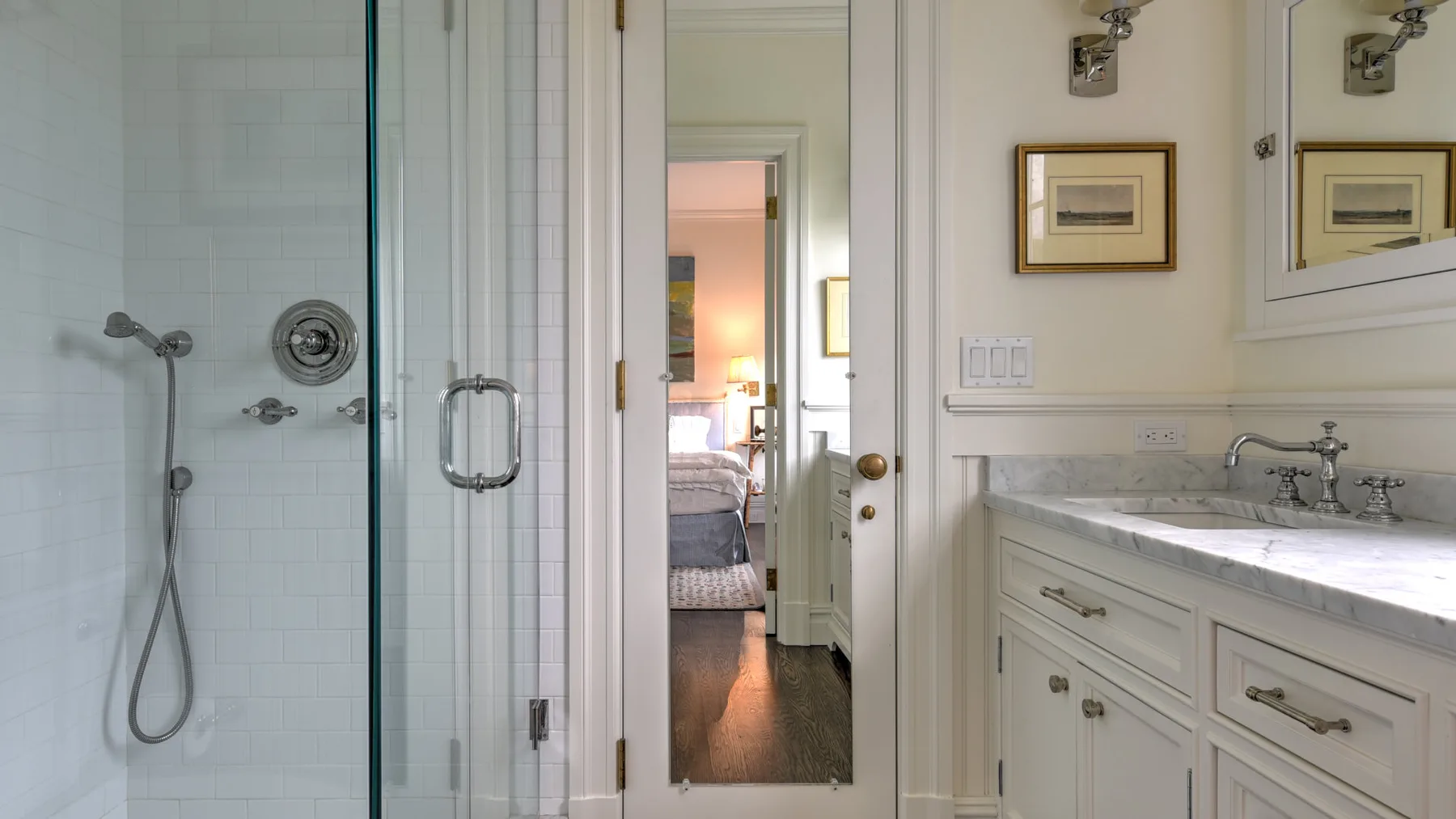 Un baño con ducha de vidrio y mueble de lavabo junto a un espejo de cuerpo entero.