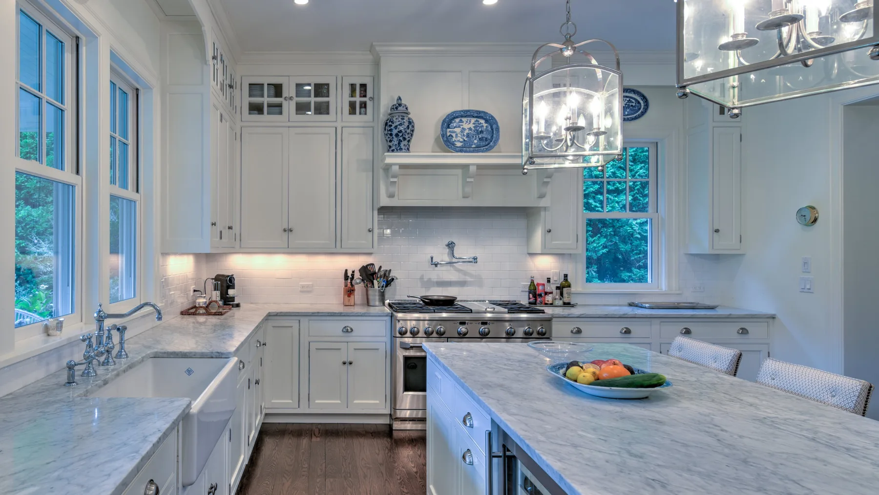 Una cocina luminosa con gabinetes blancos, ventanas amplias y una isla grande.
