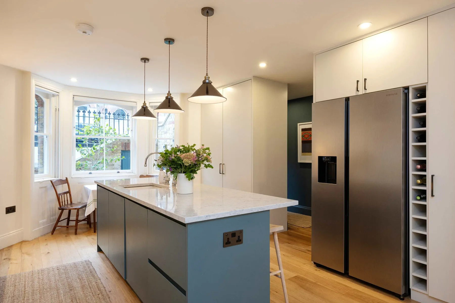 A bright kitchen with a central island, pendant lights, and large windows.