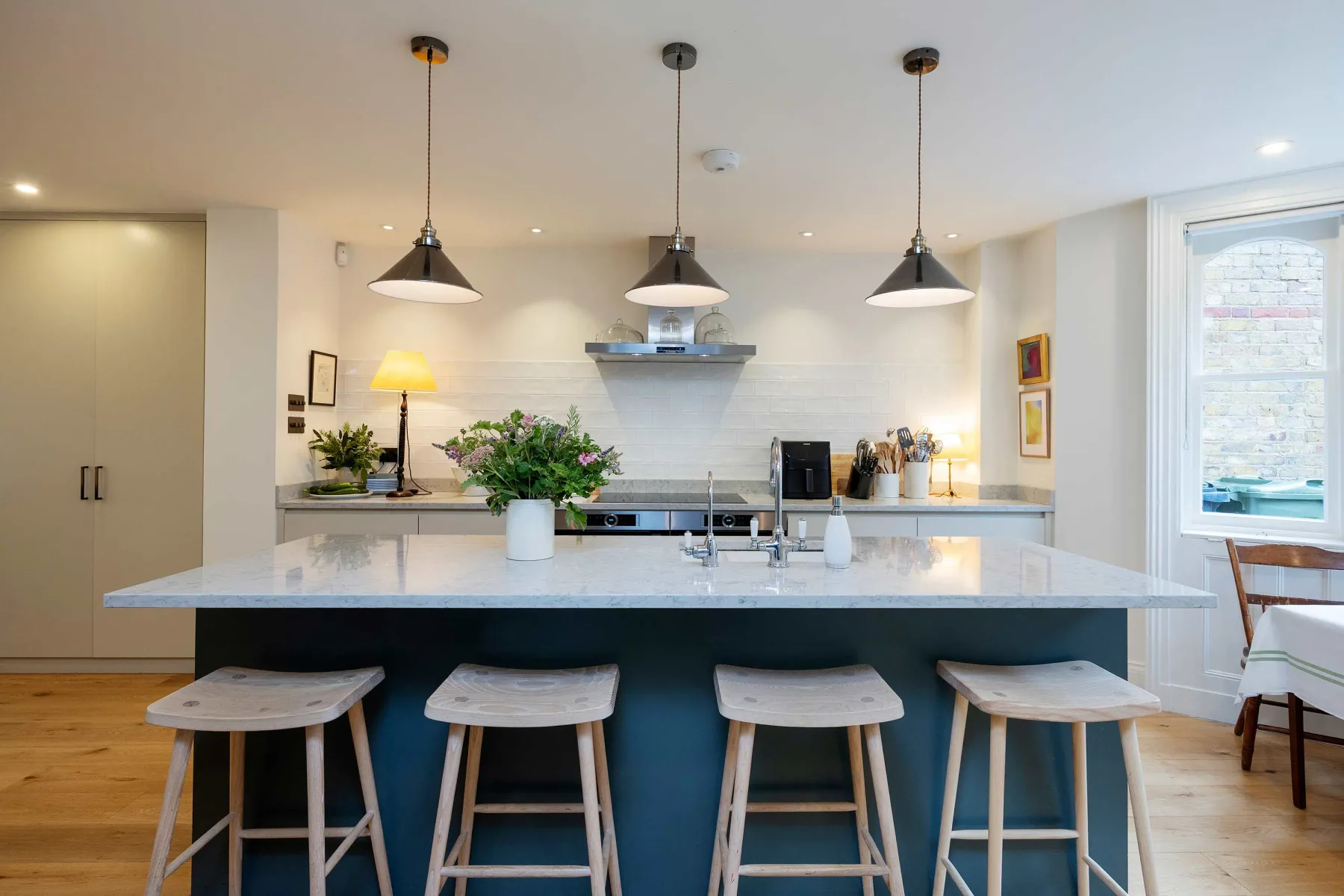 A bright kitchen with a wide island, pendant lights, and bar seating.