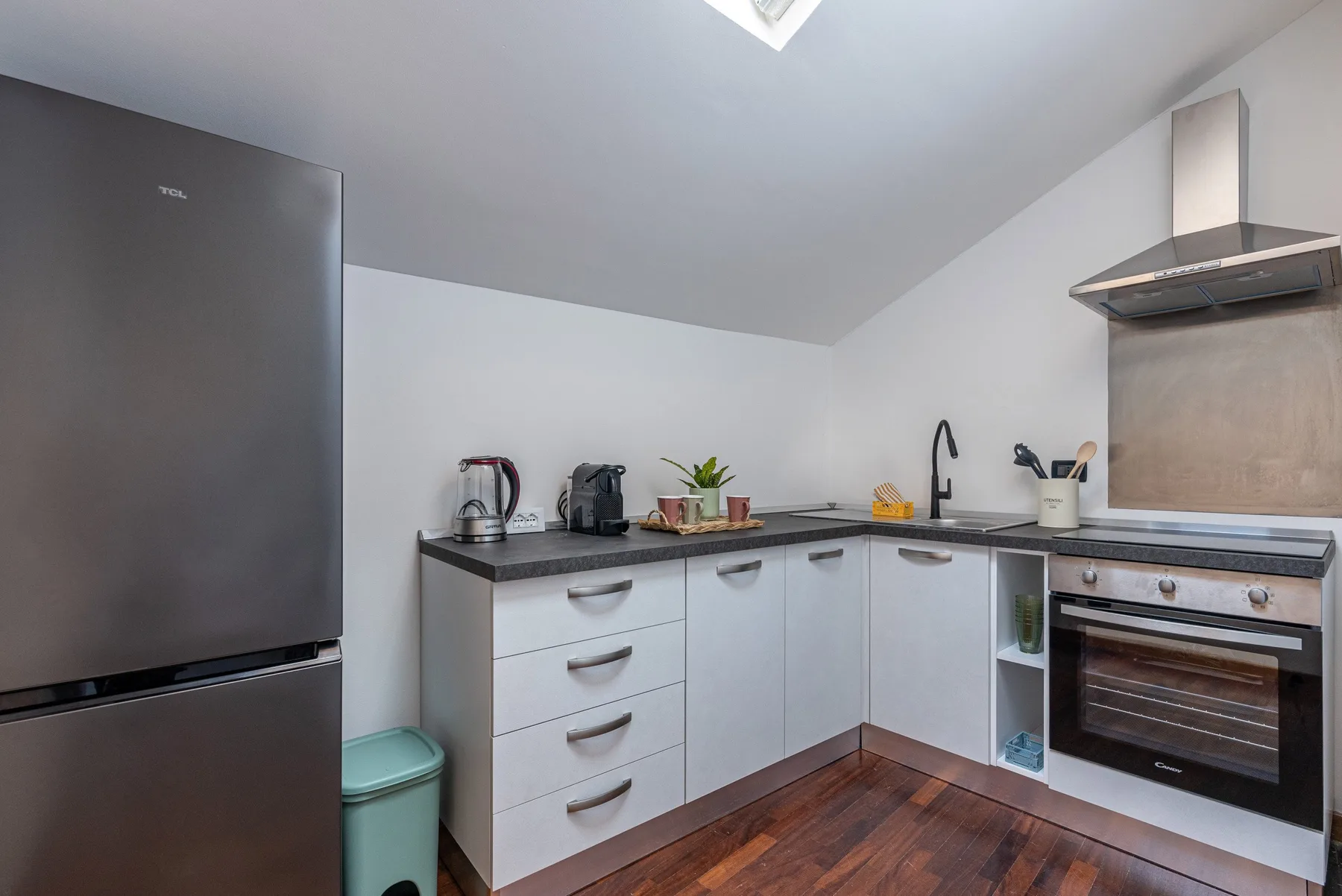 Una cocina compacta con gabinetes blancos, una encimera y un horno.