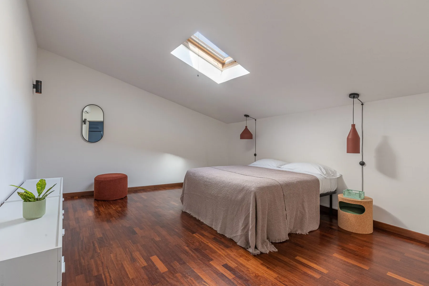 A bright bedroom with a double bed, bedside tables, and a skylight.
