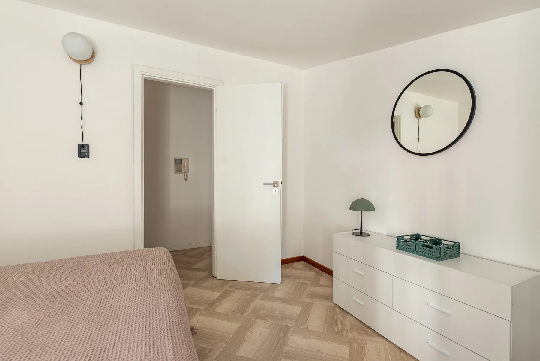 A bedroom with a bed, dresser, and an open doorway.