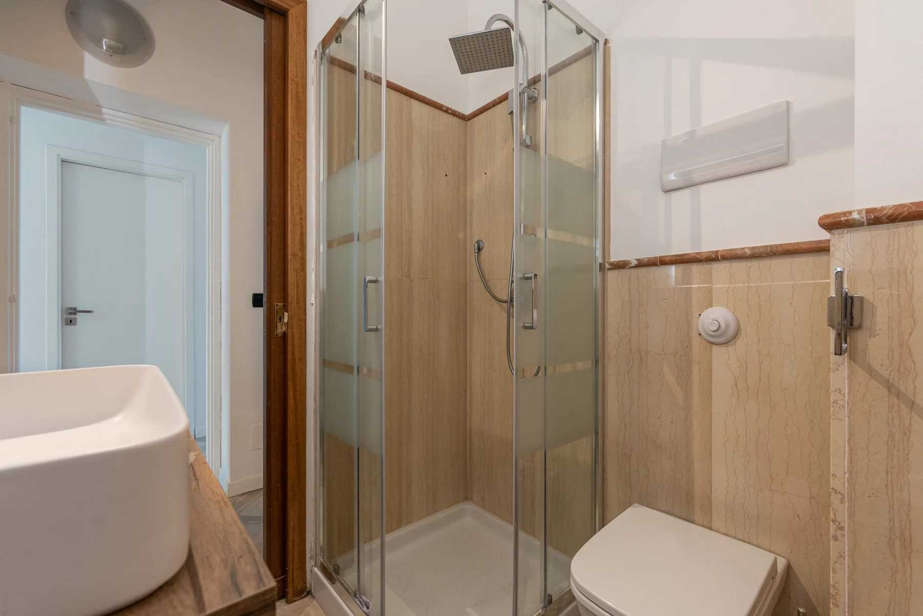 Un baño con ducha de vidrio, lavabo e inodoro.