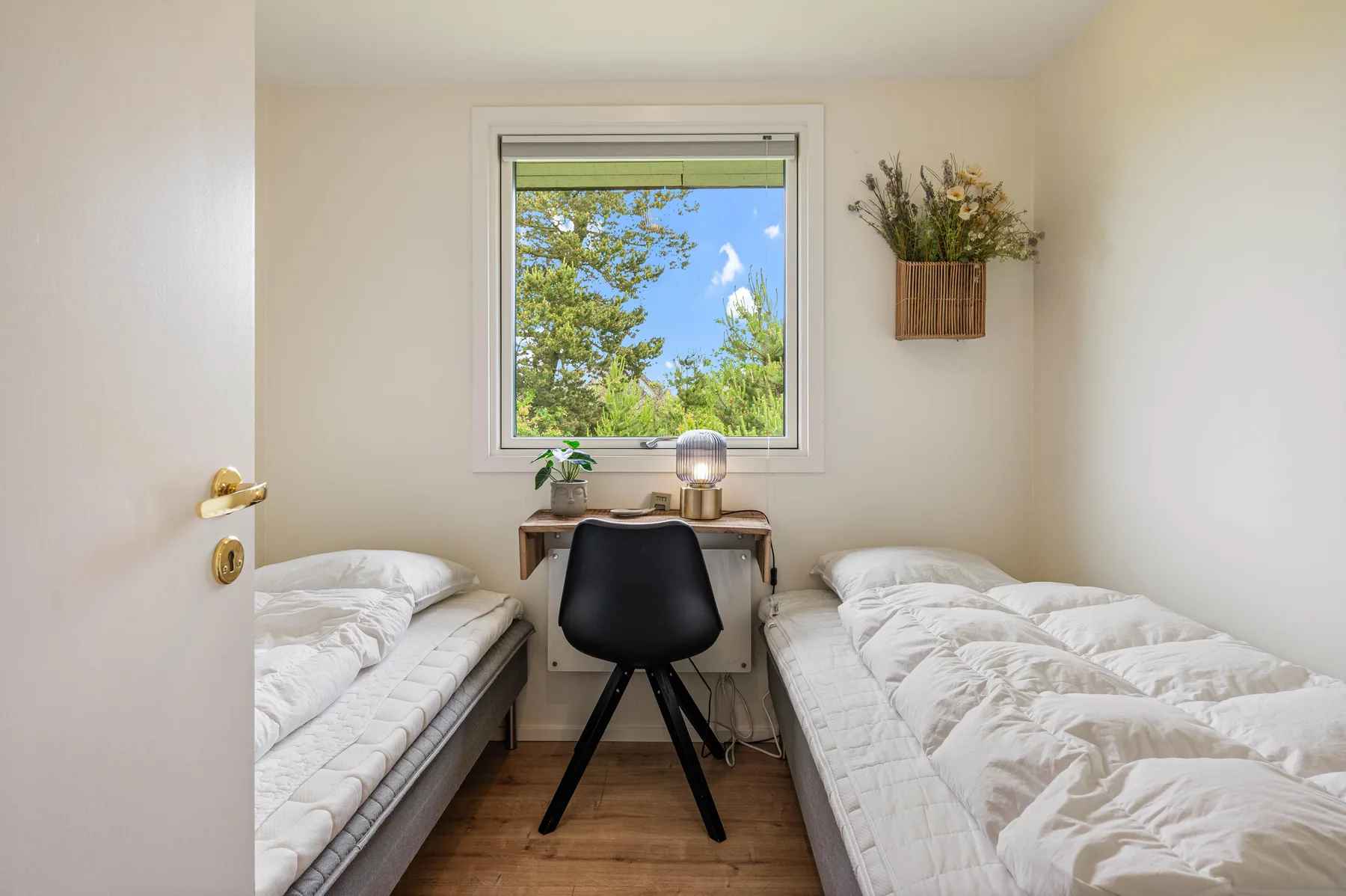 Un dormitorio con dos camas individuales y un escritorio bajo la ventana.