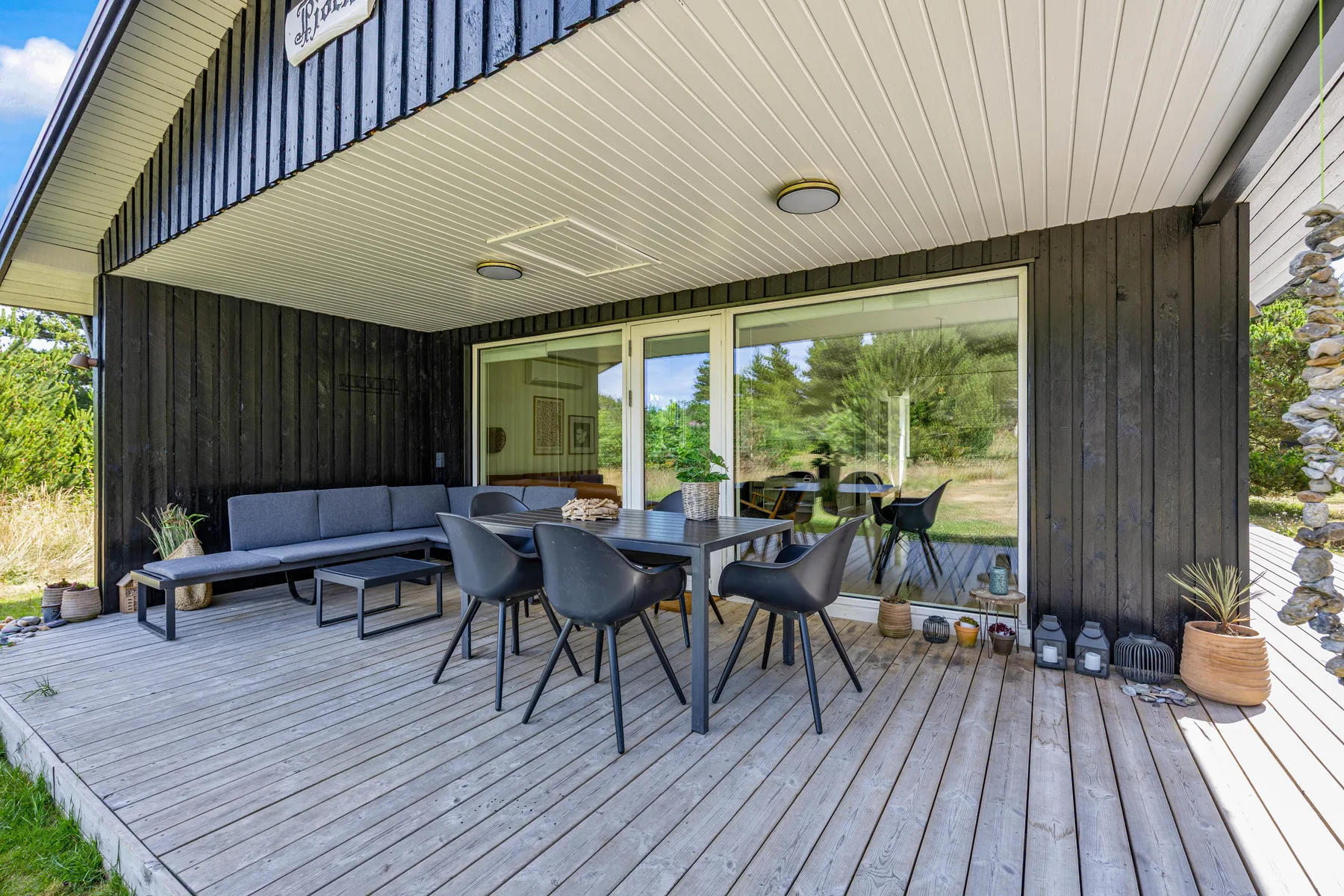 Una zona exterior cubierta con una mesa de comedor junto a grandes puertas de vidrio.