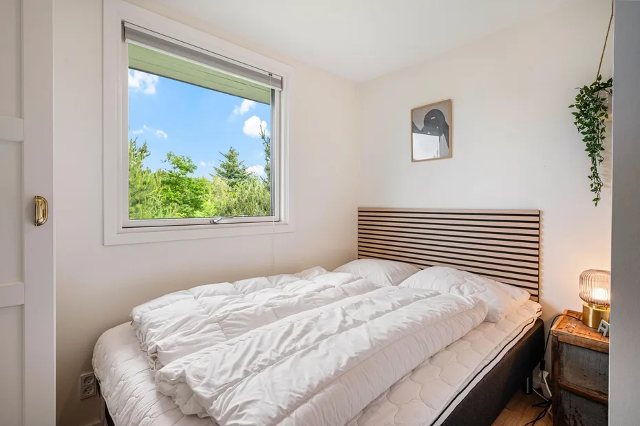 Un dormitorio con una cama bajo un cabecero de listones y una ventana.