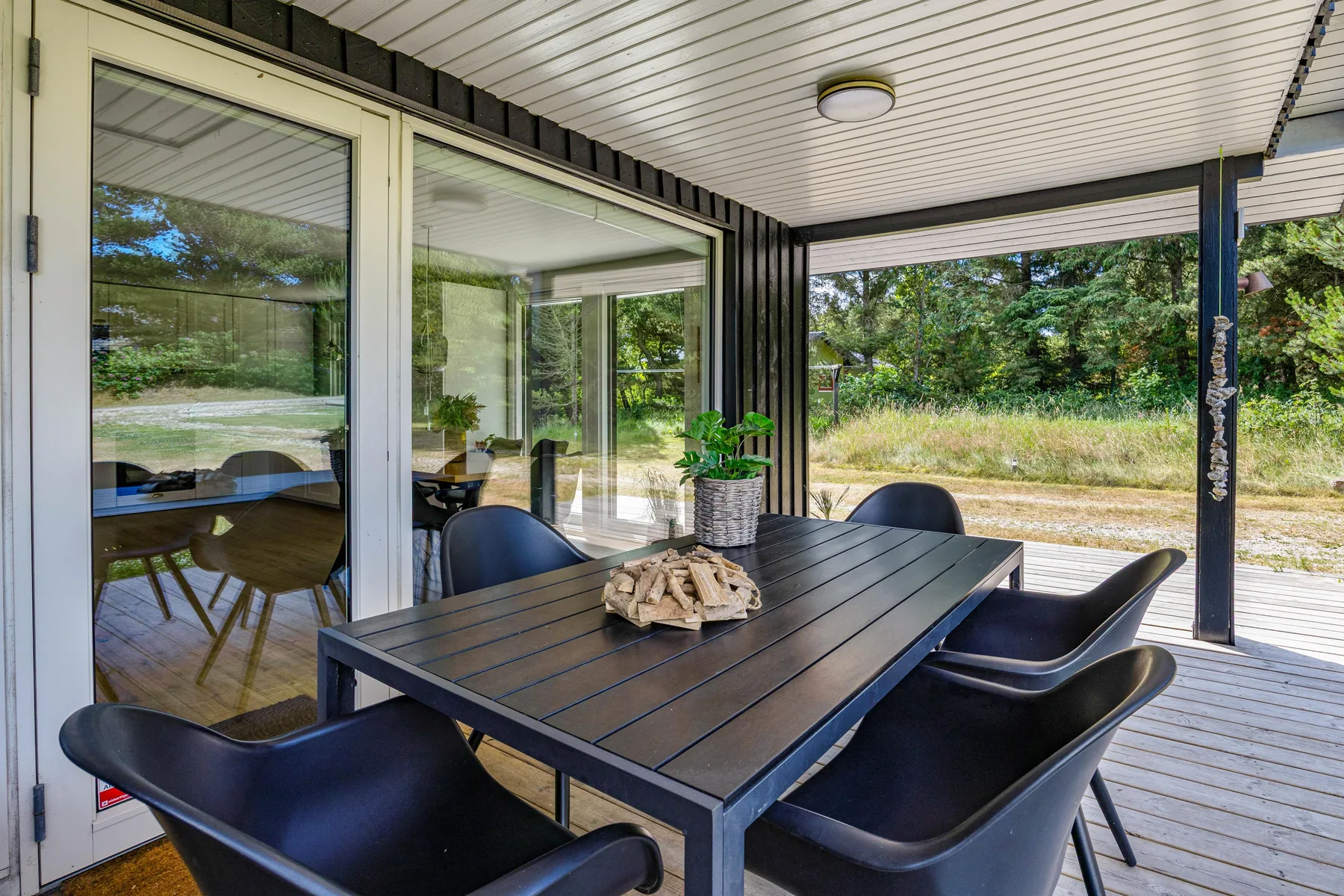 Un patio cubierto con una mesa de comedor exterior oscura y asientos.
