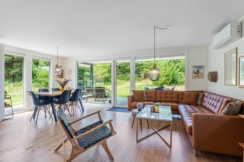 Una luminosa sala de estar y comedor diáfanos con grandes ventanas que dan a zonas verdes.