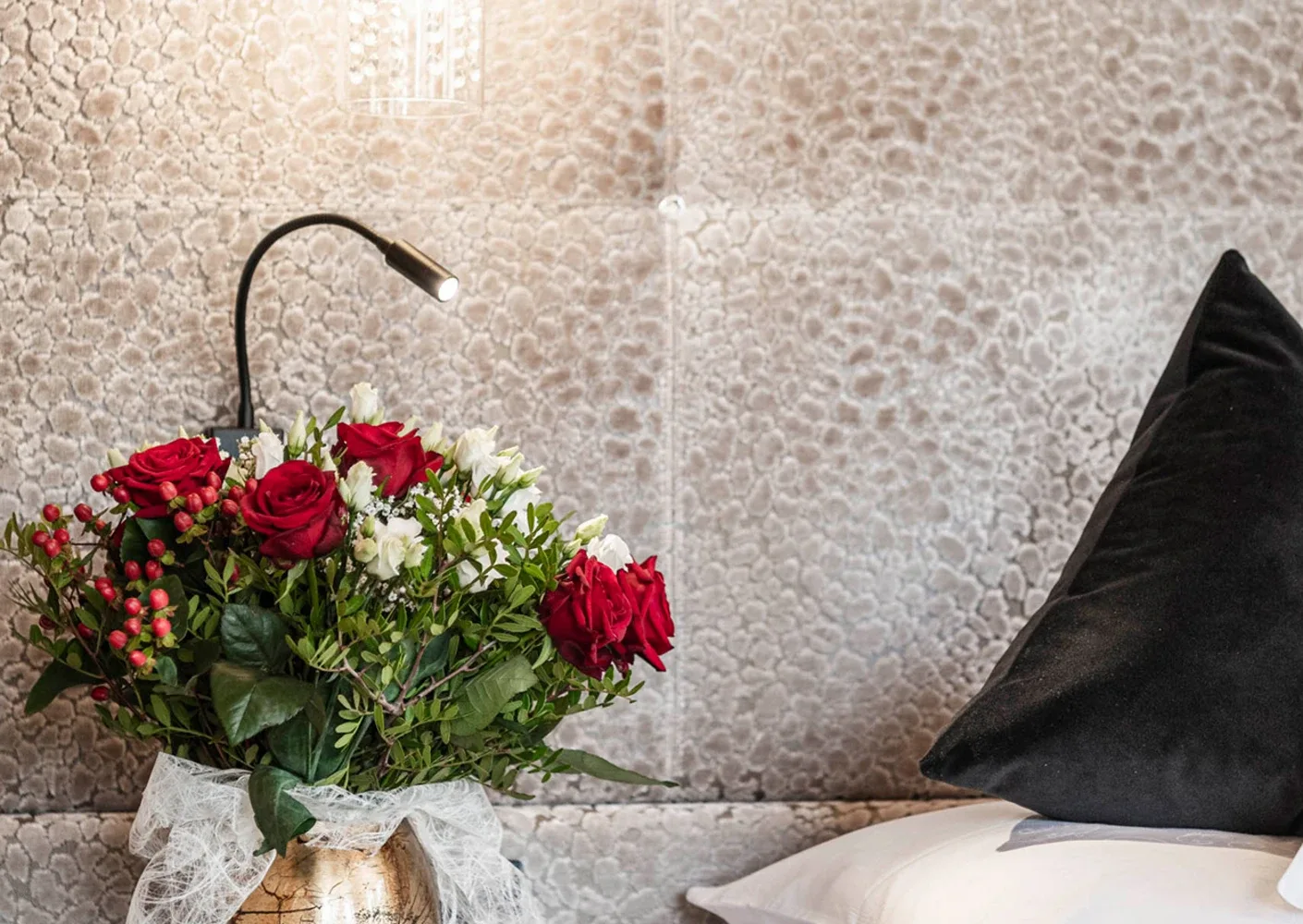 Flowers beside a hotel bed.