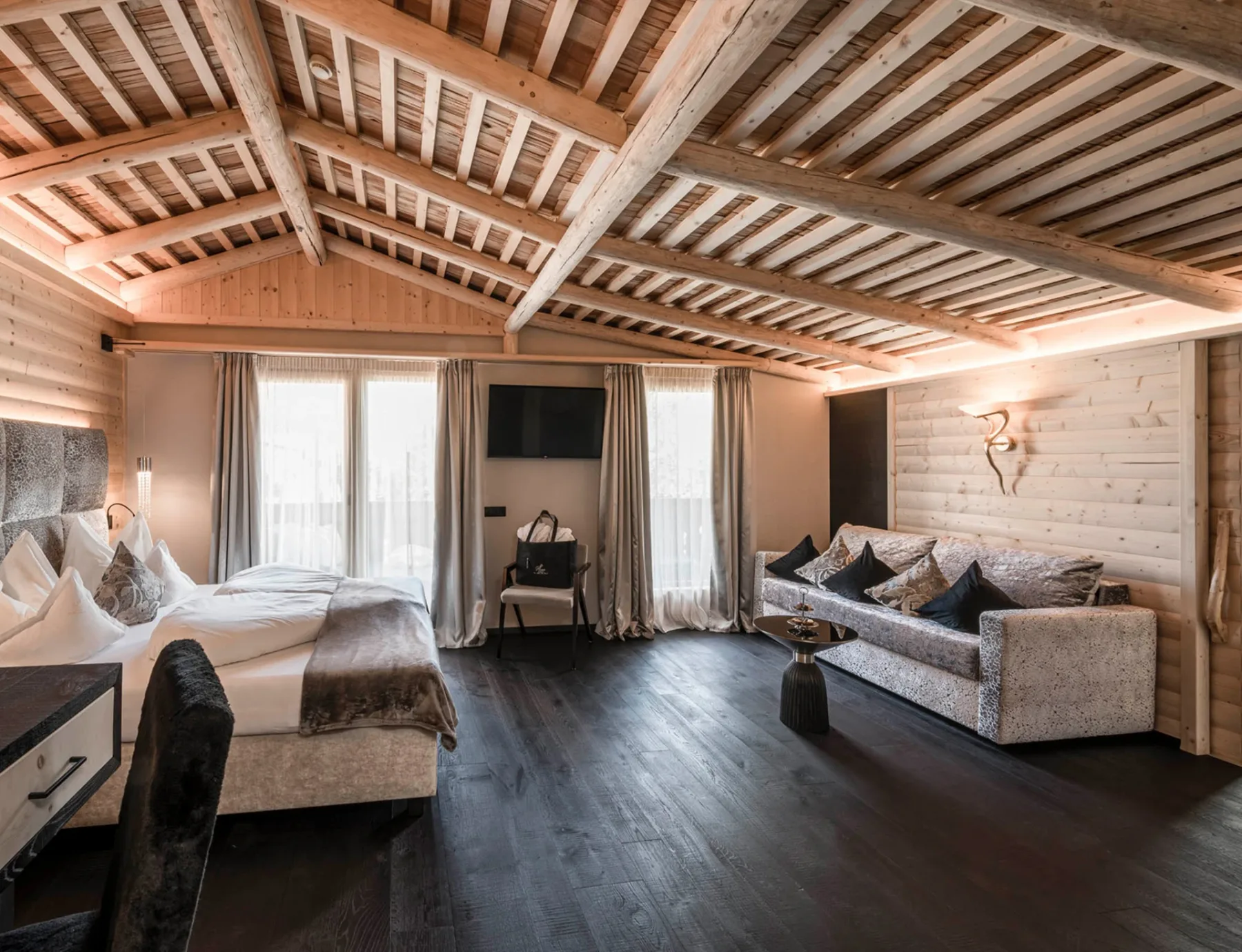 Suite Alpine Lifestyle with bed, sofa and large windows.