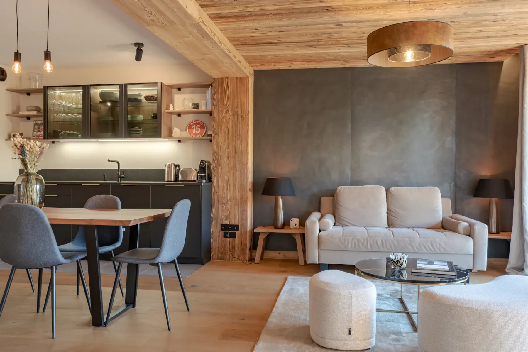 Una sala de estar con asientos claros, una mesa de centro y un comedor junto a la cocina.