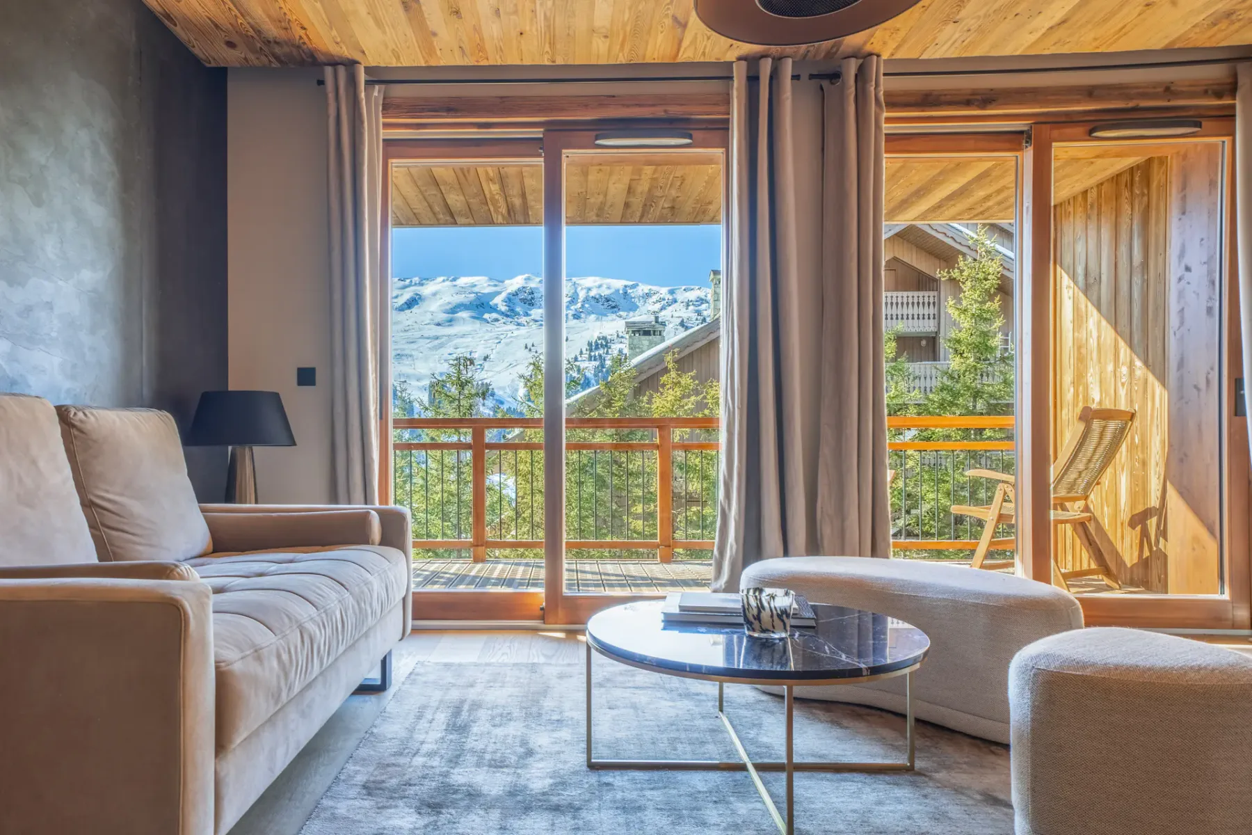 Una sala de estar con asientos y una mesa de centro de cristal junto a una ventana con vistas a las montañas.