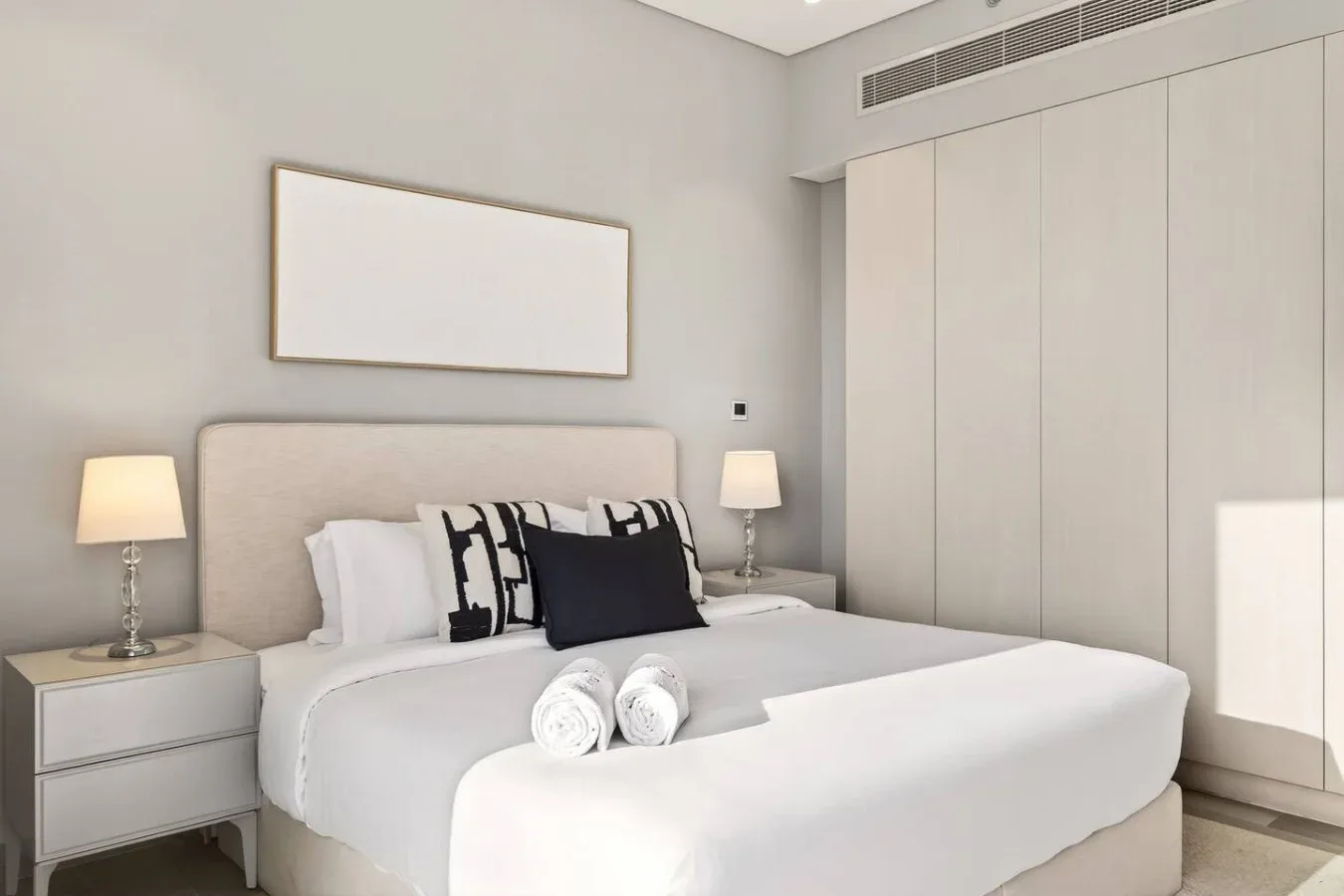 Un dormitorio luminoso con una cama bien tendida y mesitas de noche.