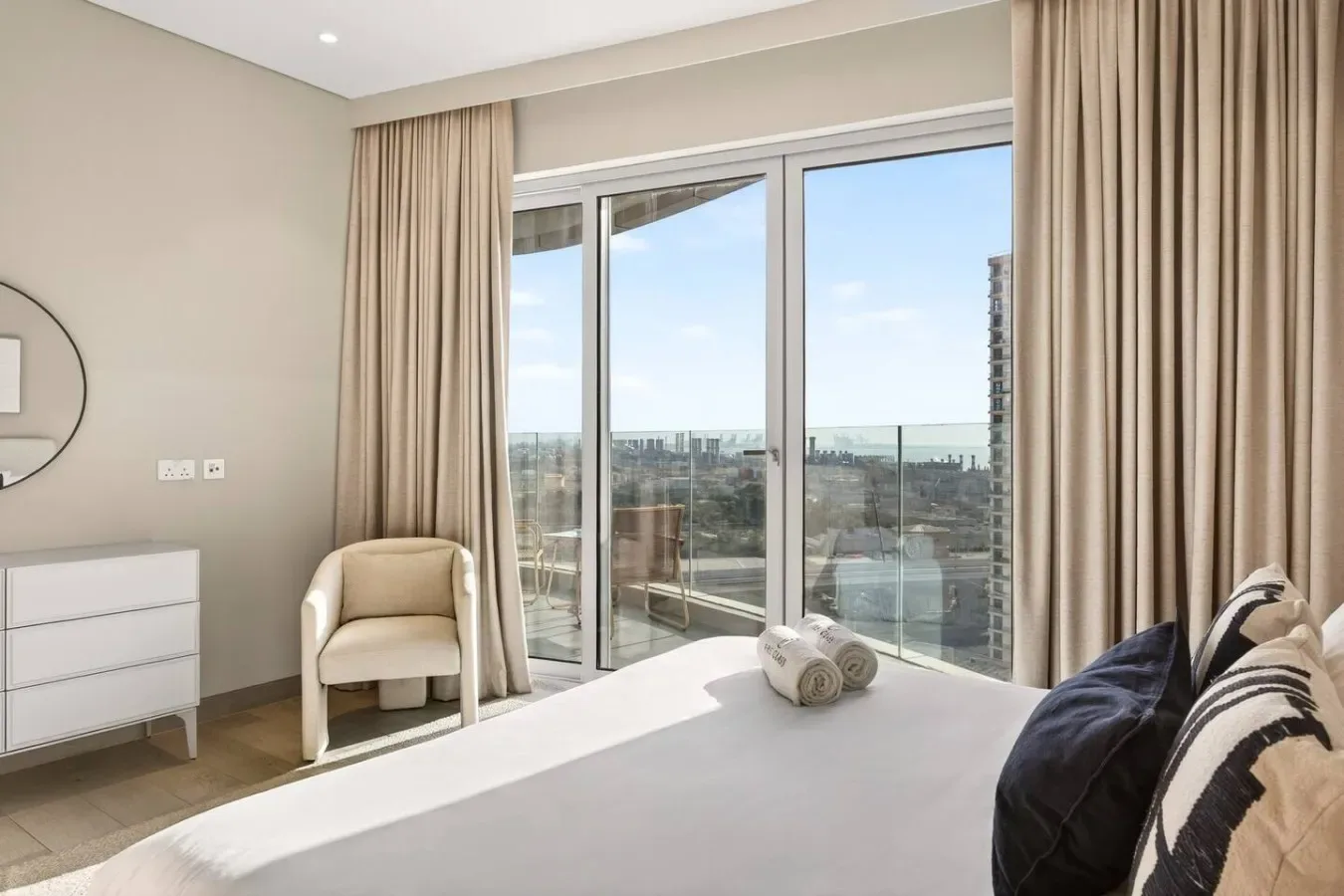 Un dormitorio luminoso con una gran ventana y cortinas con vistas a la ciudad.