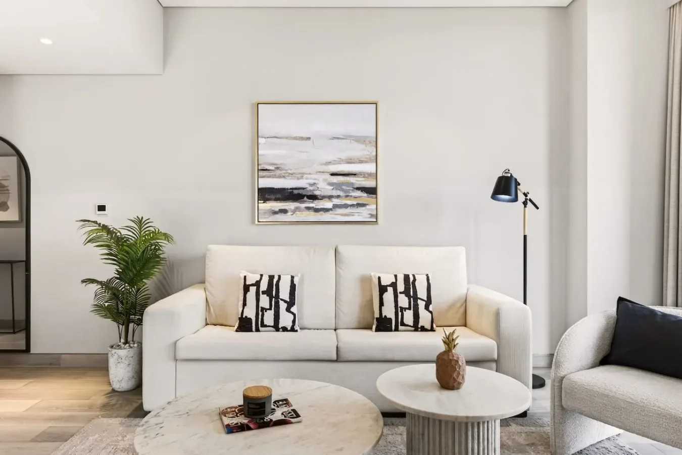 Una sala luminosa con asientos claros, una mesa de centro y arte enmarcado.
