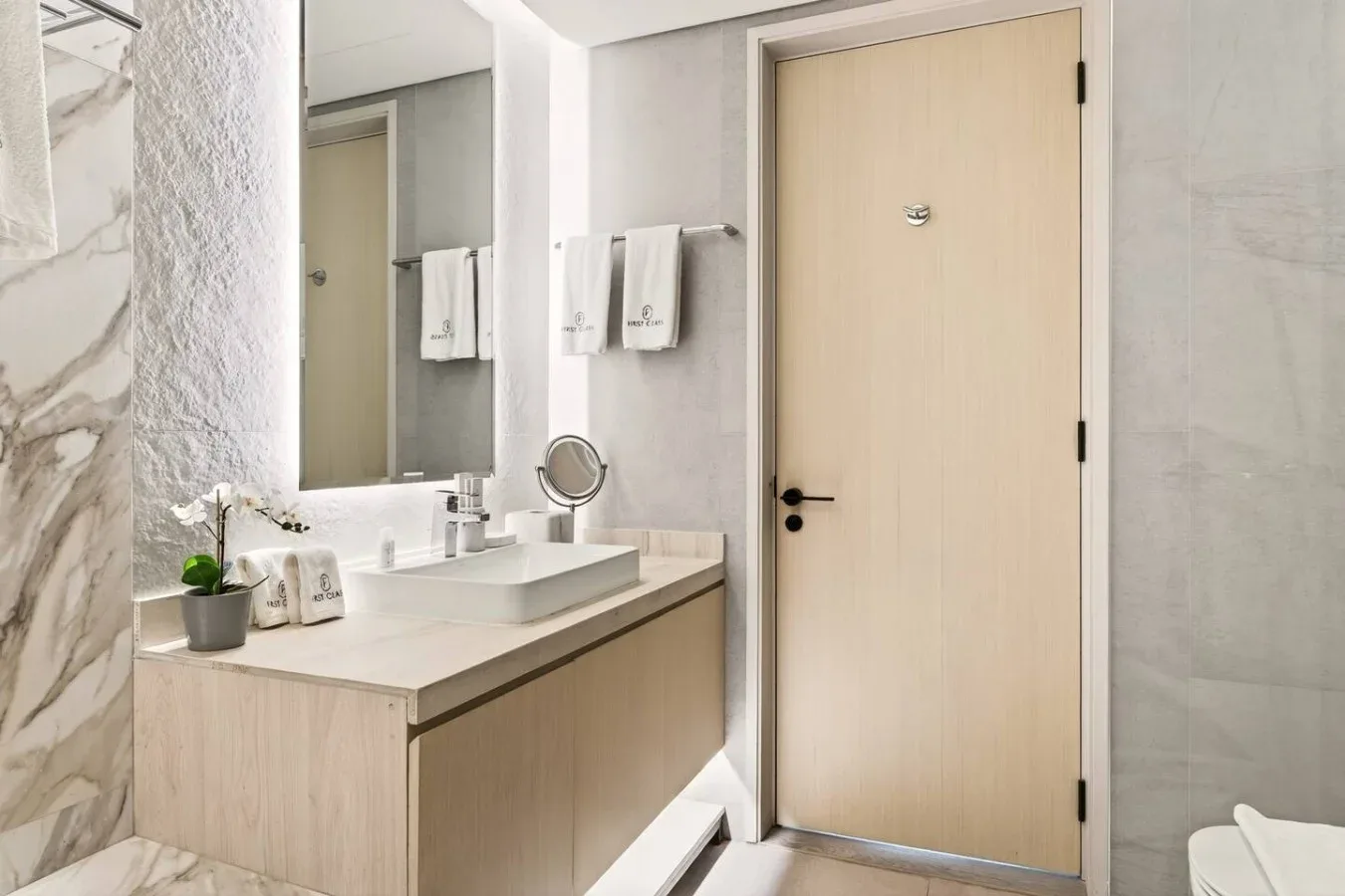 Un tocador de baño con espejo y una puerta cerrada.